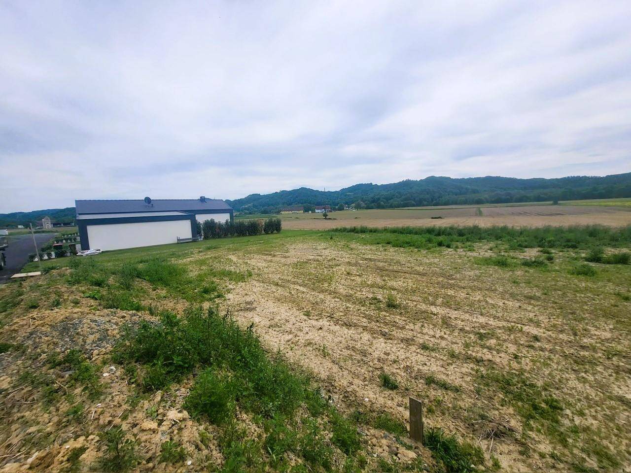 Weitläufige Landschaft mit Feldern und einem modernen Haus am Horizont.