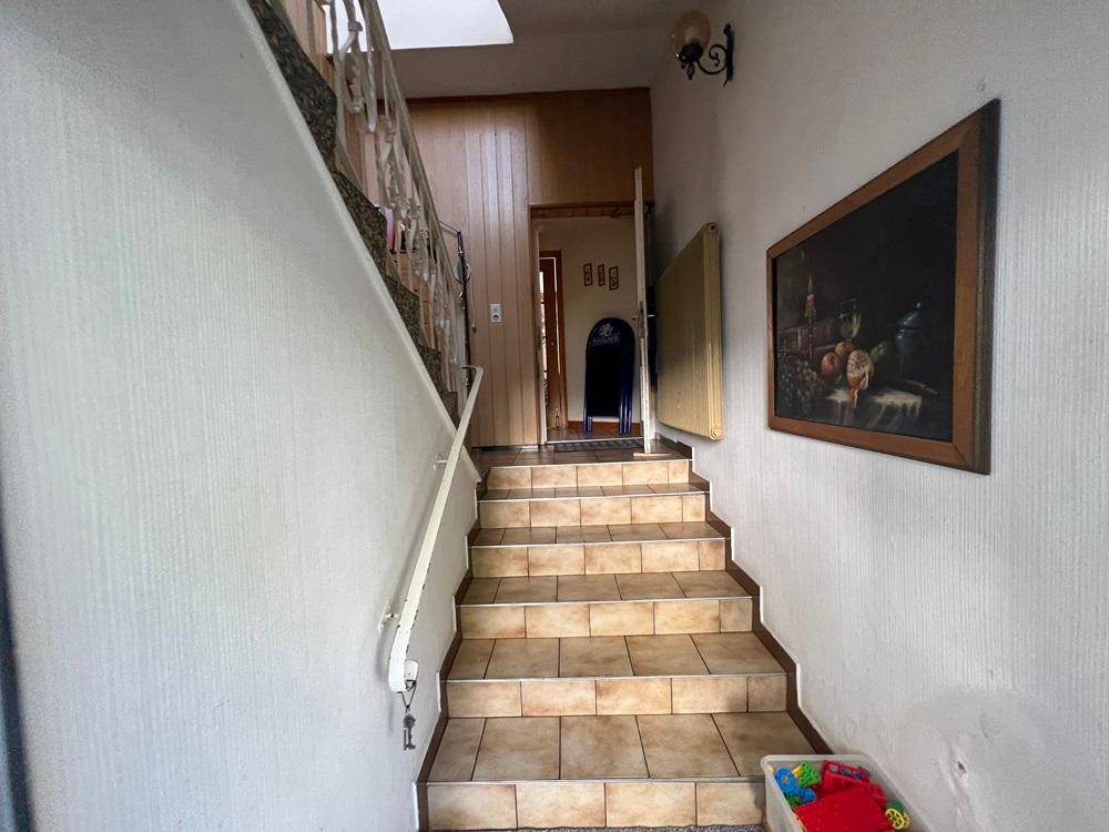 Treppenhaus mit gefliesten Stufen, Holzvertäfelung und einem Geländer im traditionellen Stil.