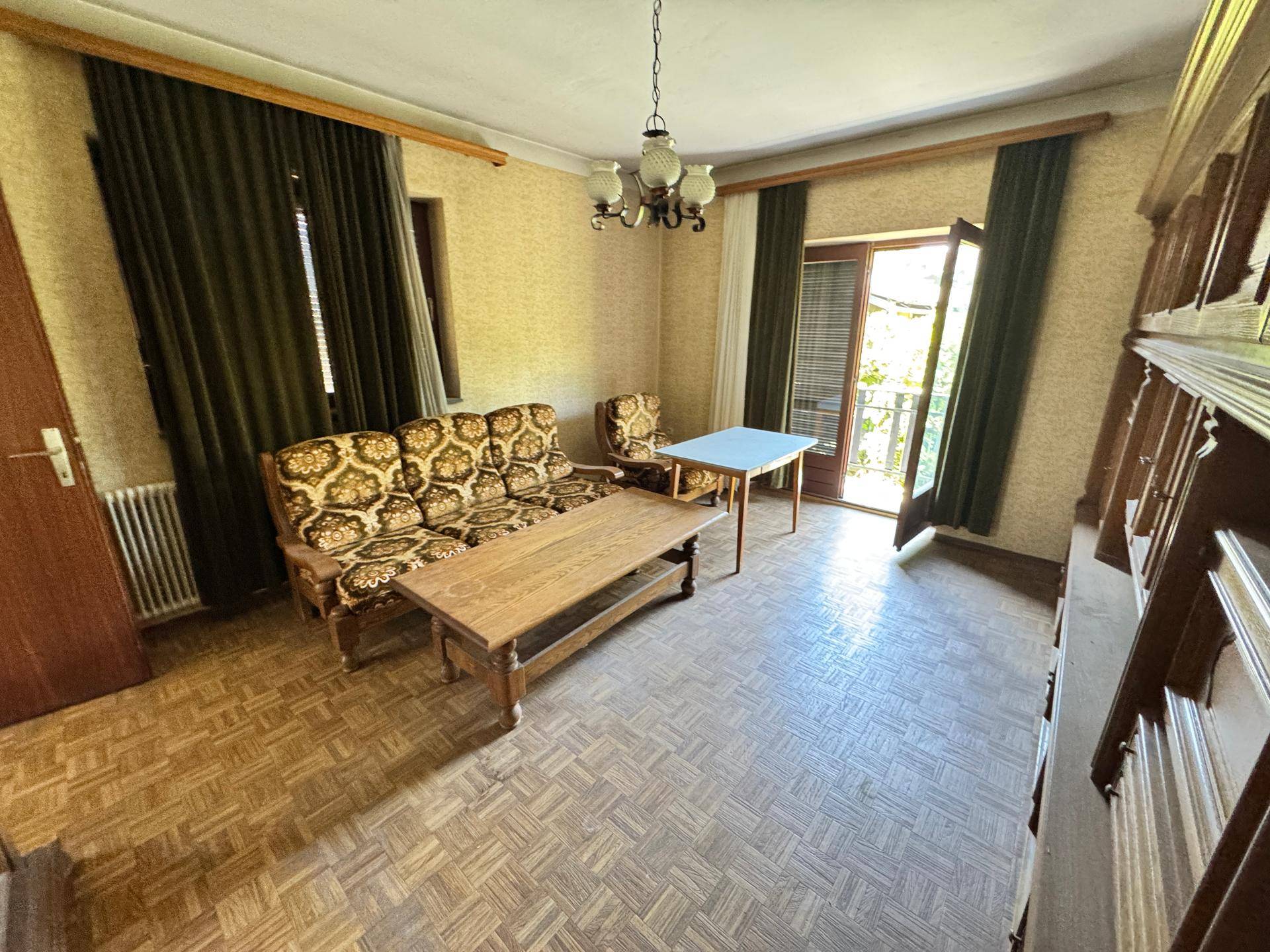 Wohnzimmer mit traditionellen Möbeln, gemustertem Boden und Balkonzugang.