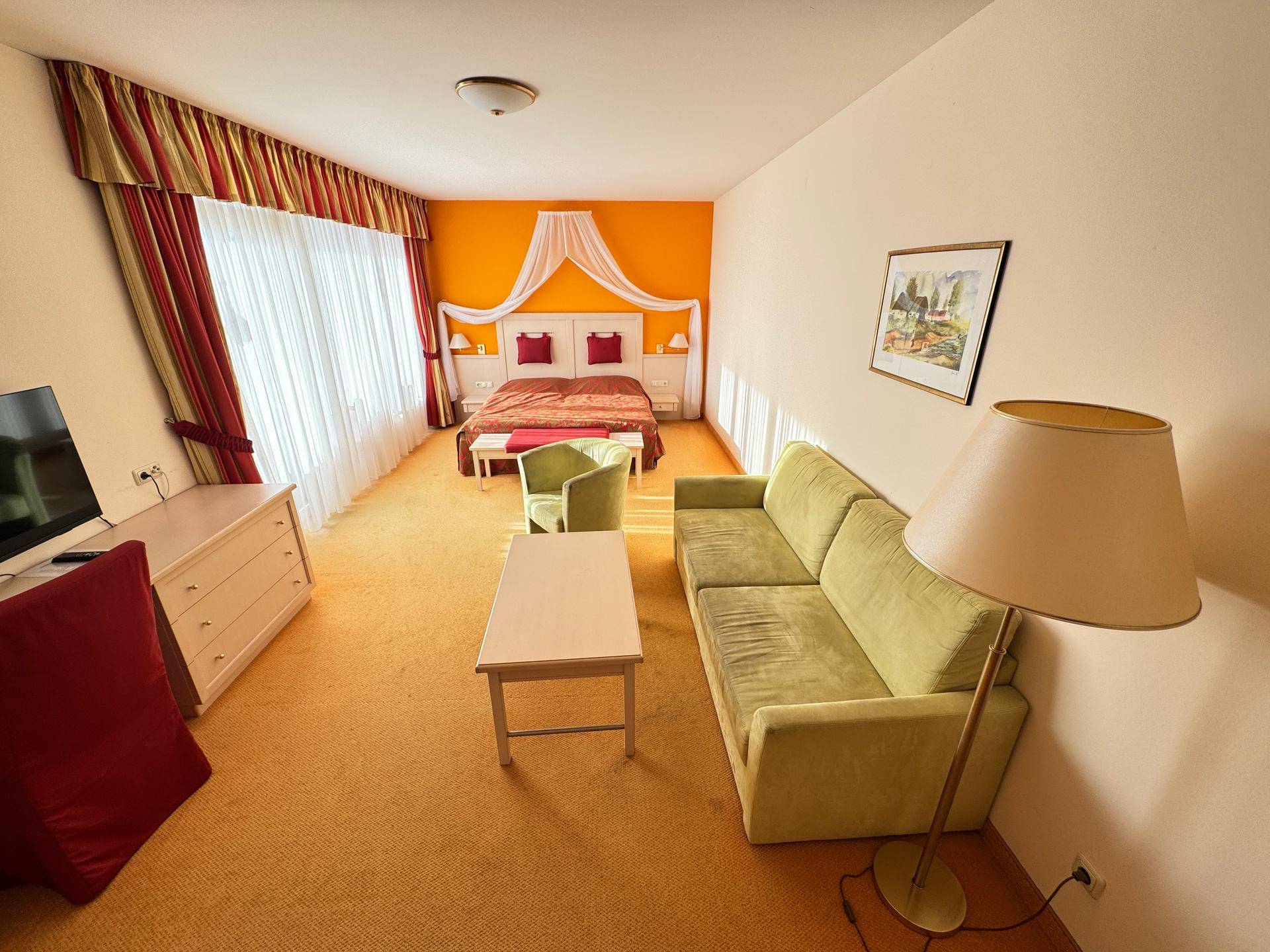 Schlafzimmer mit Doppelbett, Sofa und Teppichboden.