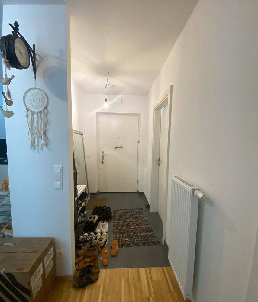 Heller Eingangsbereich mit Holzboden, Garderobe und Heizkörper.