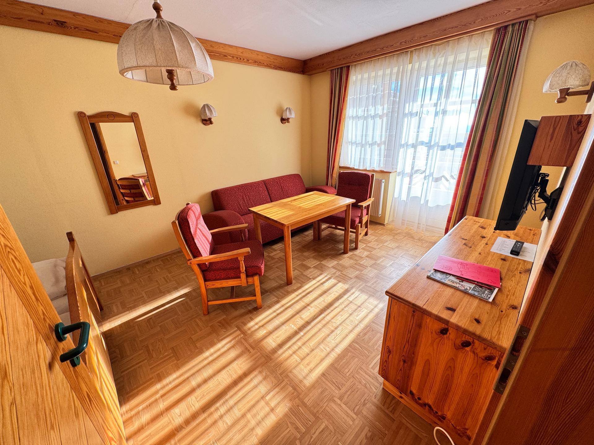 Wohnzimmer mit rustikalen Holzmöbeln und gefliestem Boden.