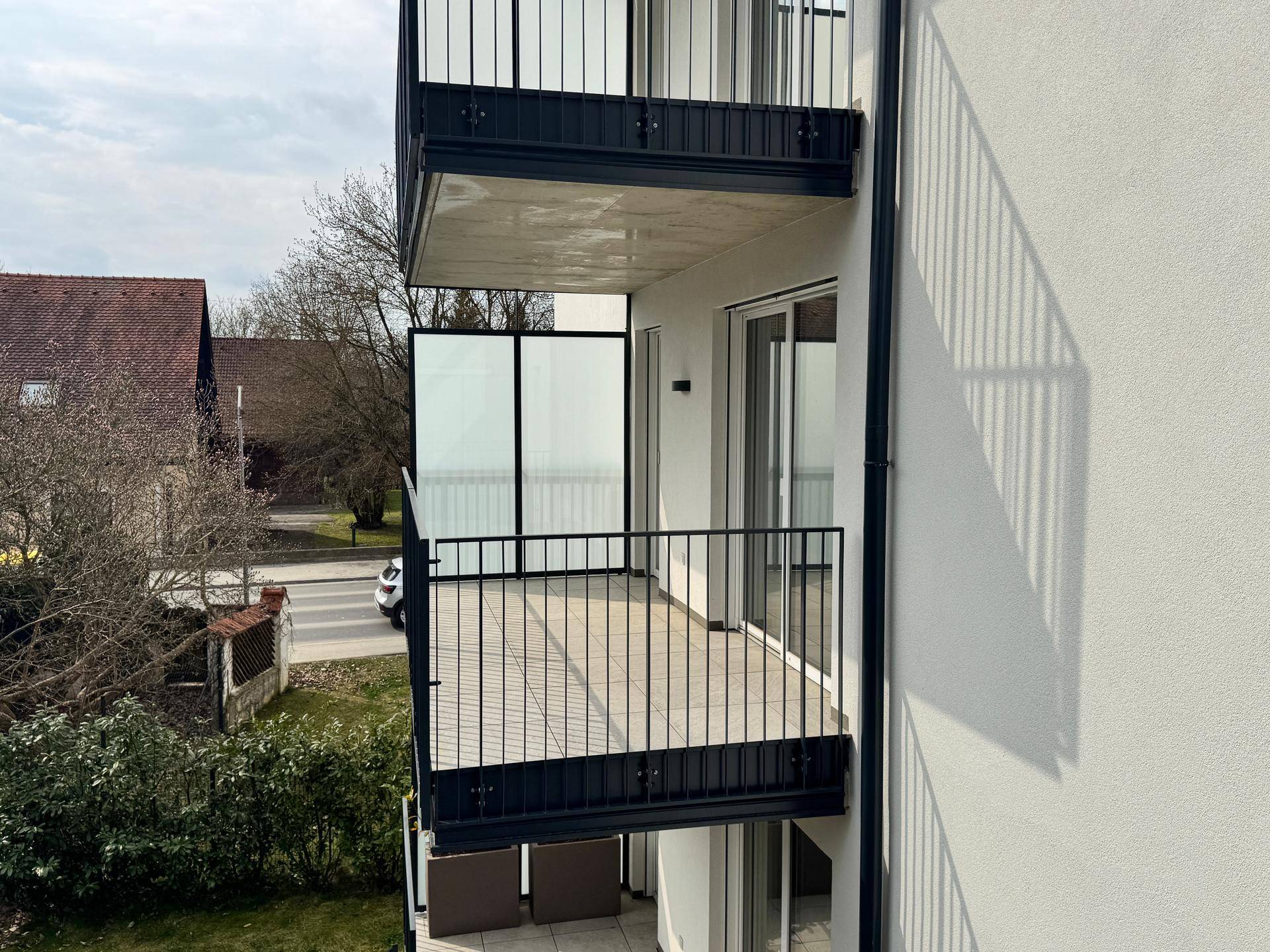 Ansicht der Gebäudeseite mit übereinanderliegenden Balkonen, teilweise mit Holzbelag.