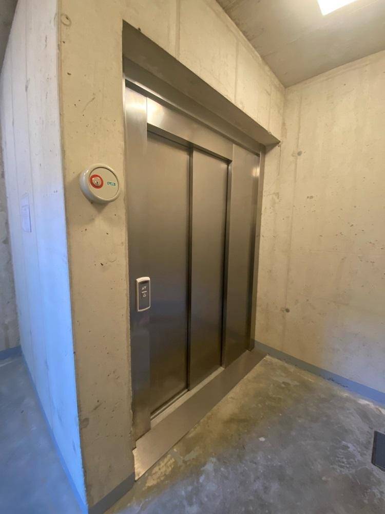 Moderner Aufzug in einem Gemeinschaftsbereich mit Betonwänden.