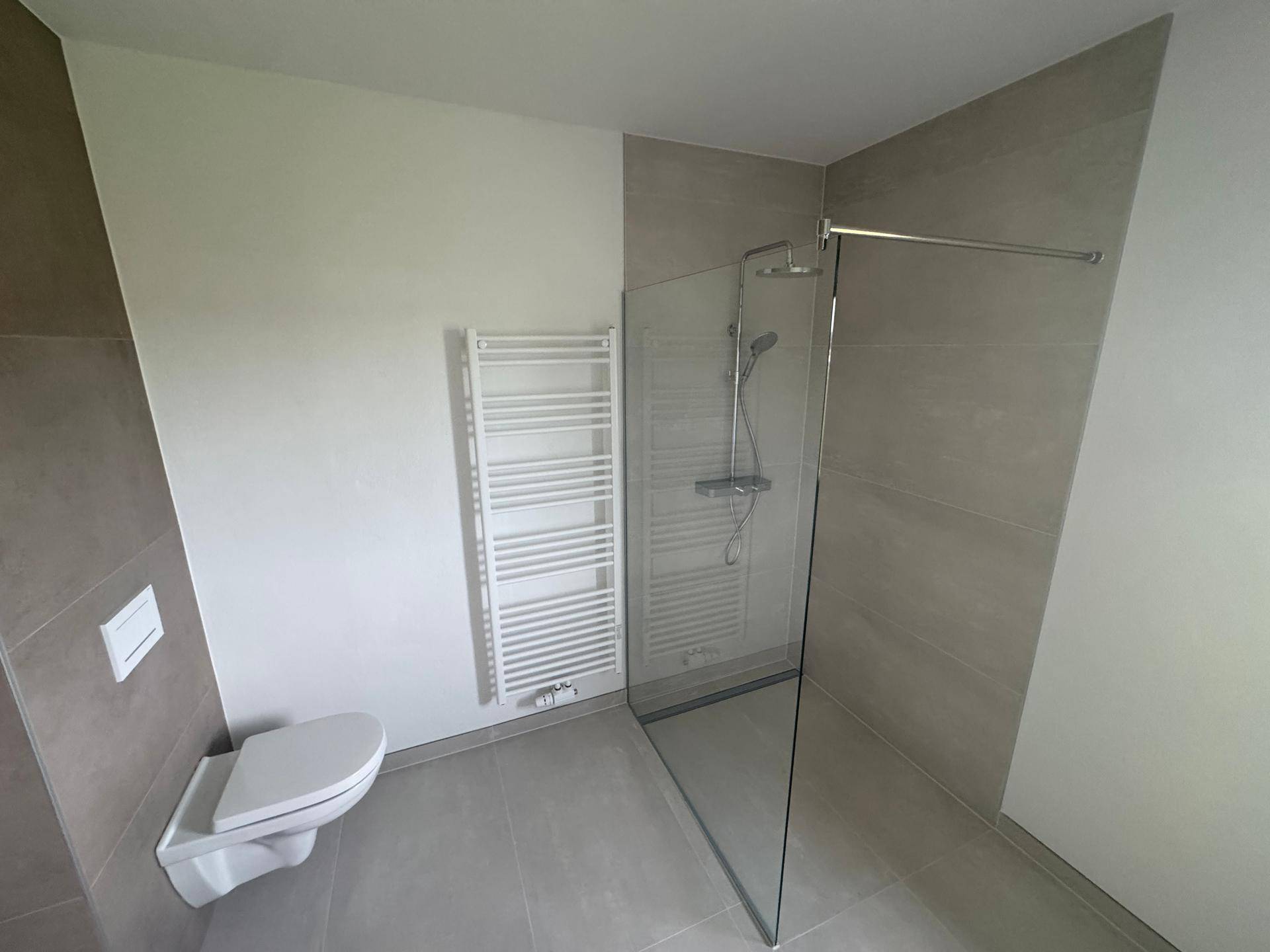 Modernes Badezimmer mit ebenerdiger Dusche, Wand-WC und beheiztem Handtuchhalter.