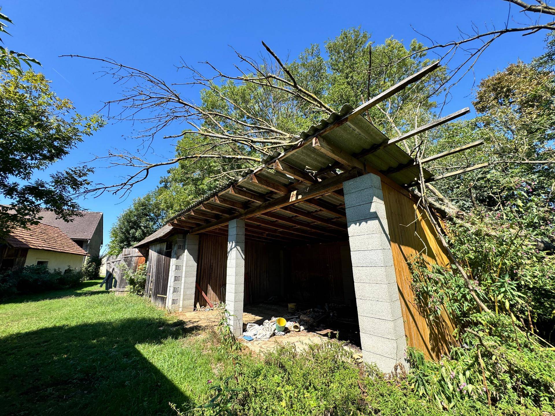 Offener Unterstand oder Schuppen mit Holzbalken und Wellblechdach.