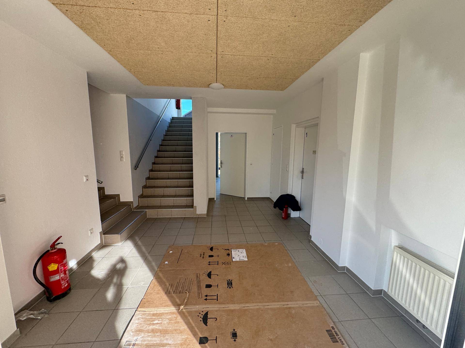 Geräumiger Eingangsbereich mit Treppenaufgang und Fliesenboden.