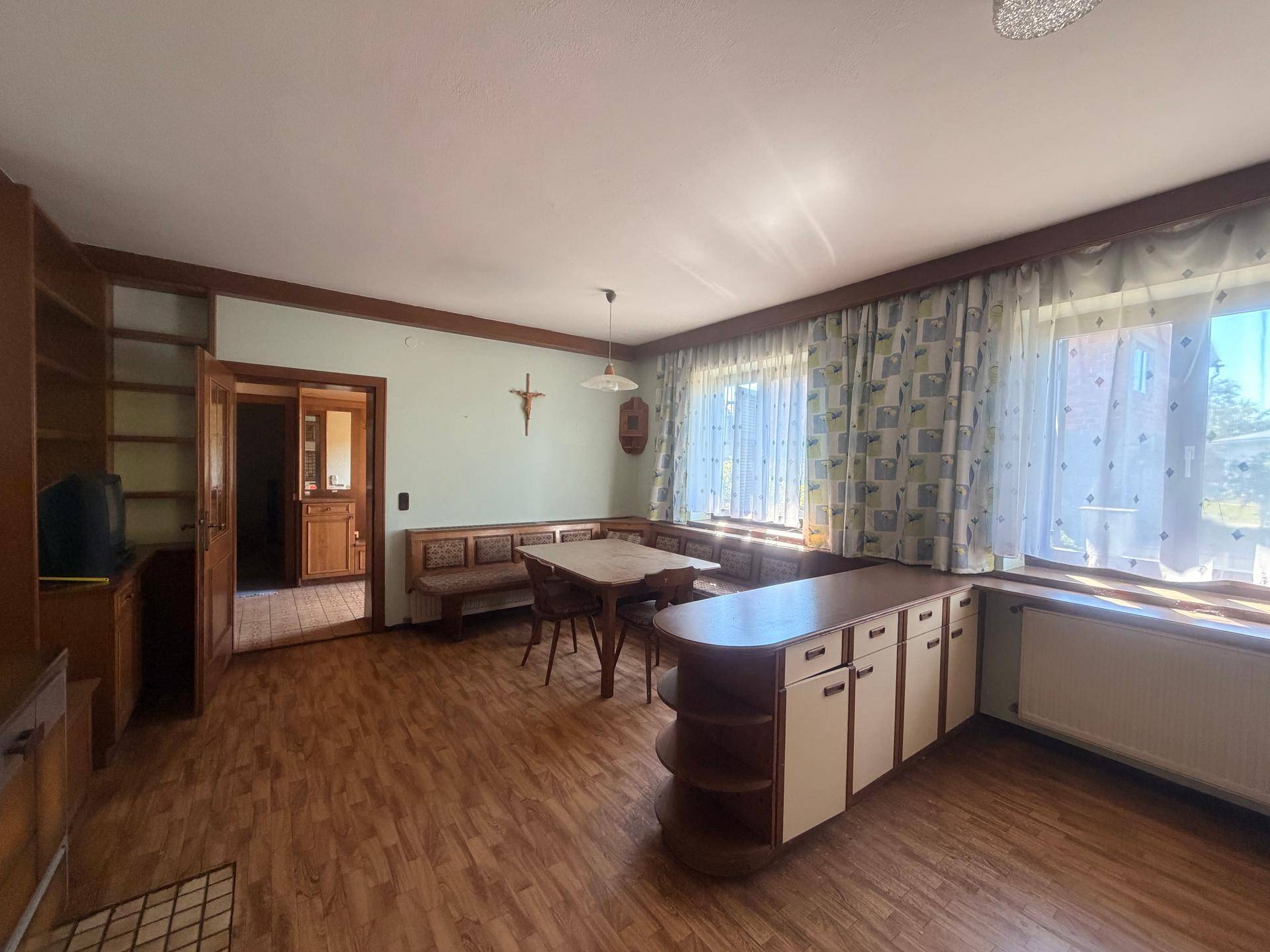 Essbereich mit Holztisch, Eckbank und Fenster mit Vorhängen, hell und gemütlich.
