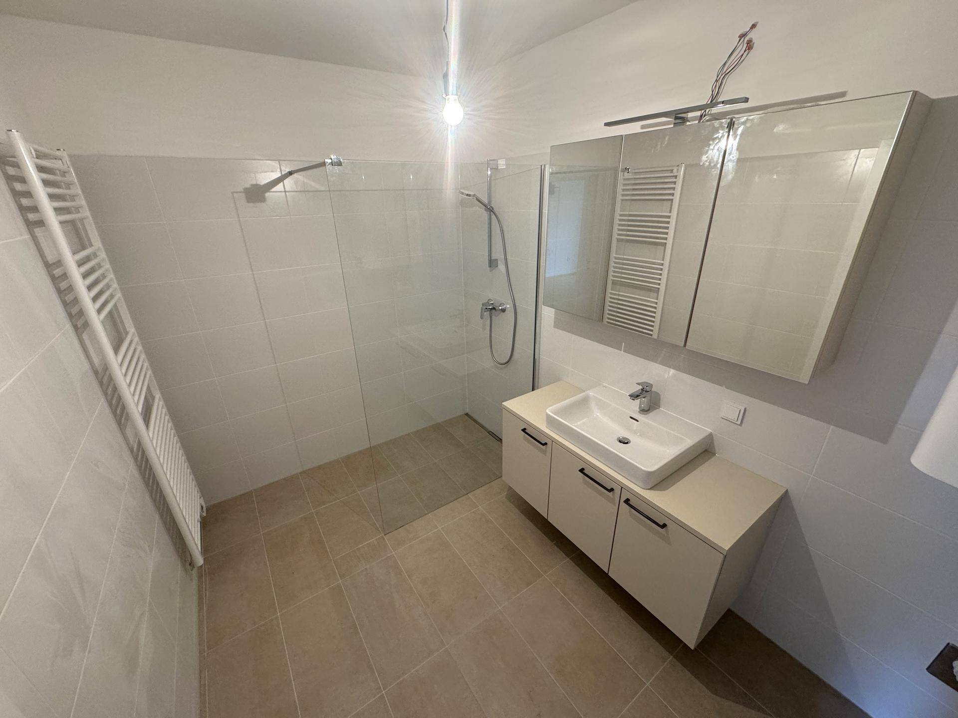 Modernes Badezimmer mit ebenerdiger Dusche, Waschtisch und beheiztem Handtuchhalter.