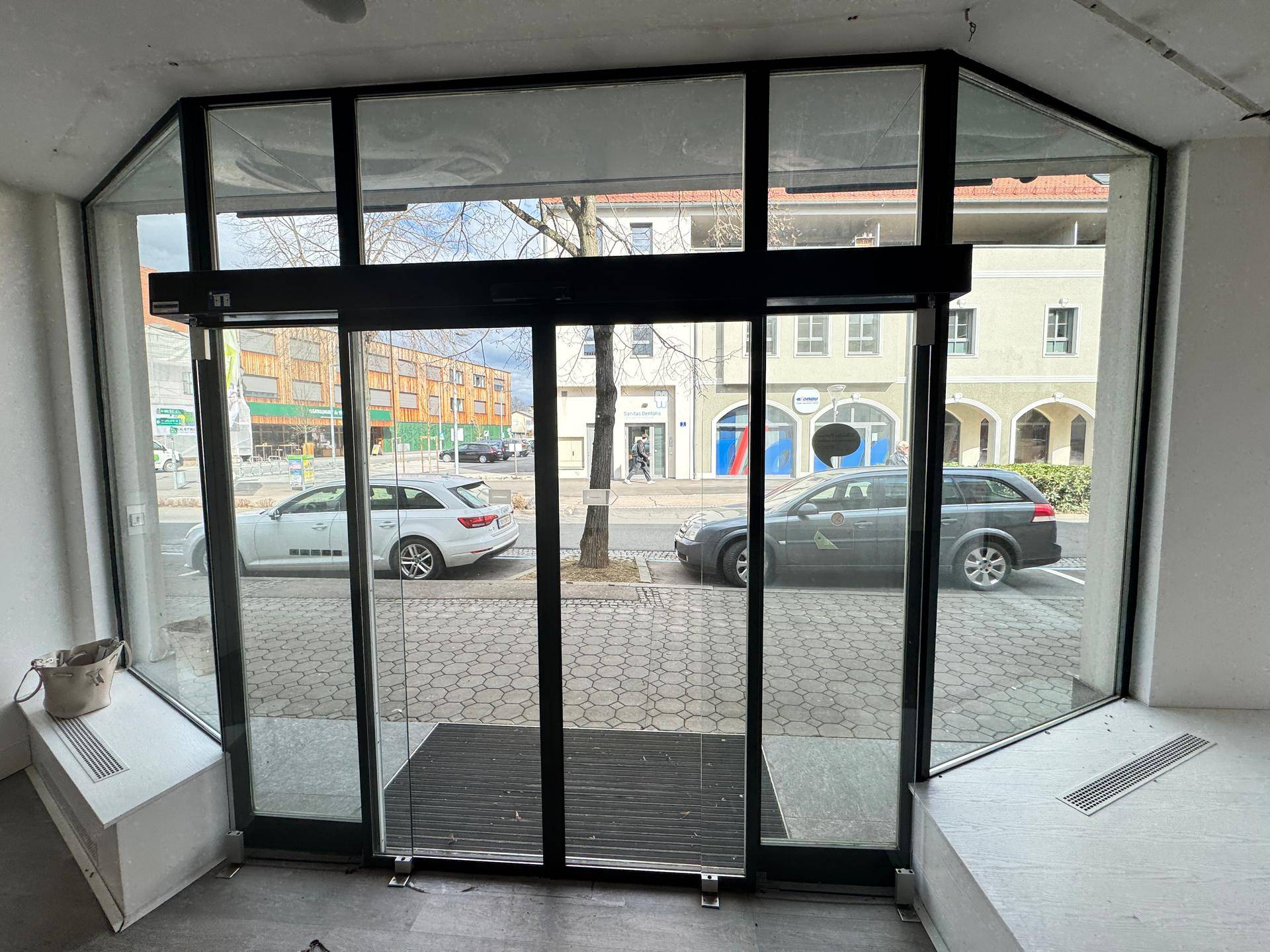 Innenansicht des Eingangsbereichs mit Blick durch die Glasfront auf die Straße.