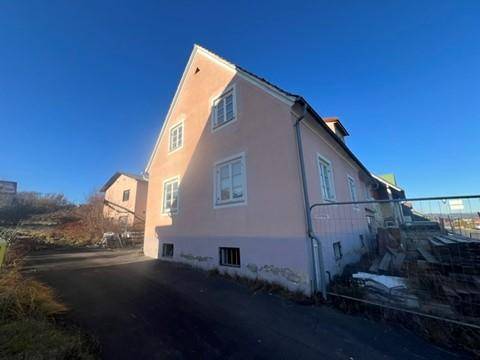 Giebelseite des rosa Hauses mit mehreren Fenstern und einem dunklen Dach.