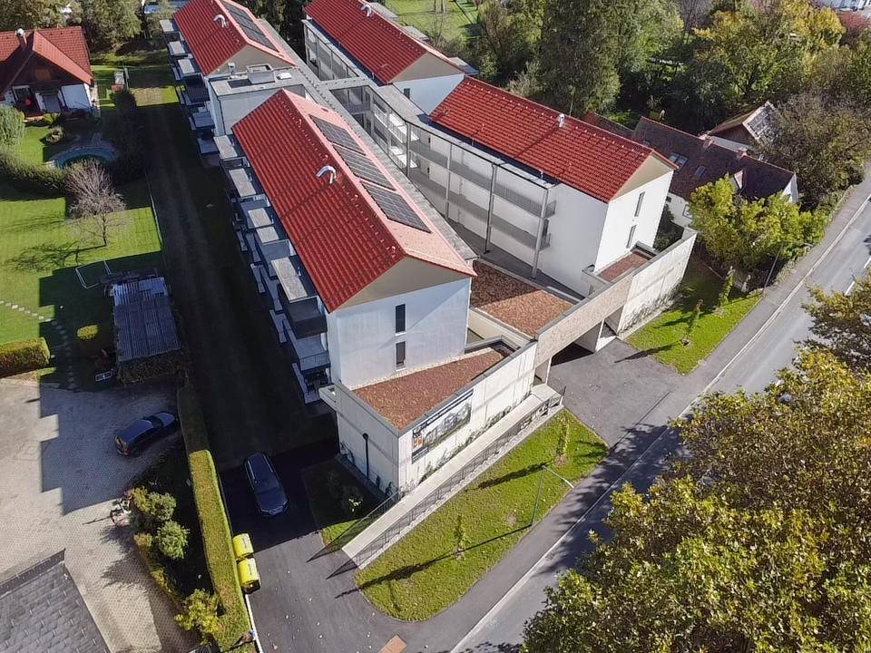 Moderne Wohnanlage mit mehreren Balkonen und Grünflächen unter blauem Himmel.