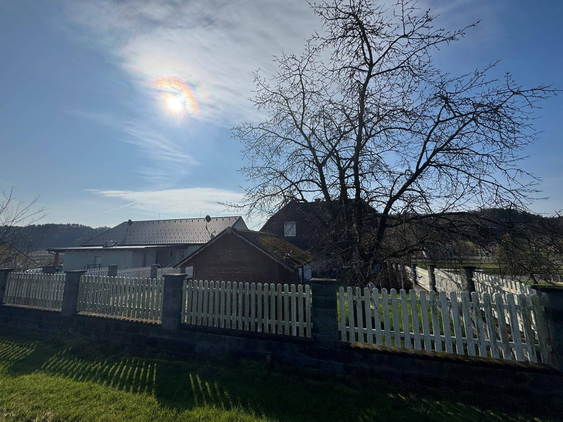 Weitwinkelaufnahme des Hauses und der umliegenden Natur mit hellem Sonnenschein.