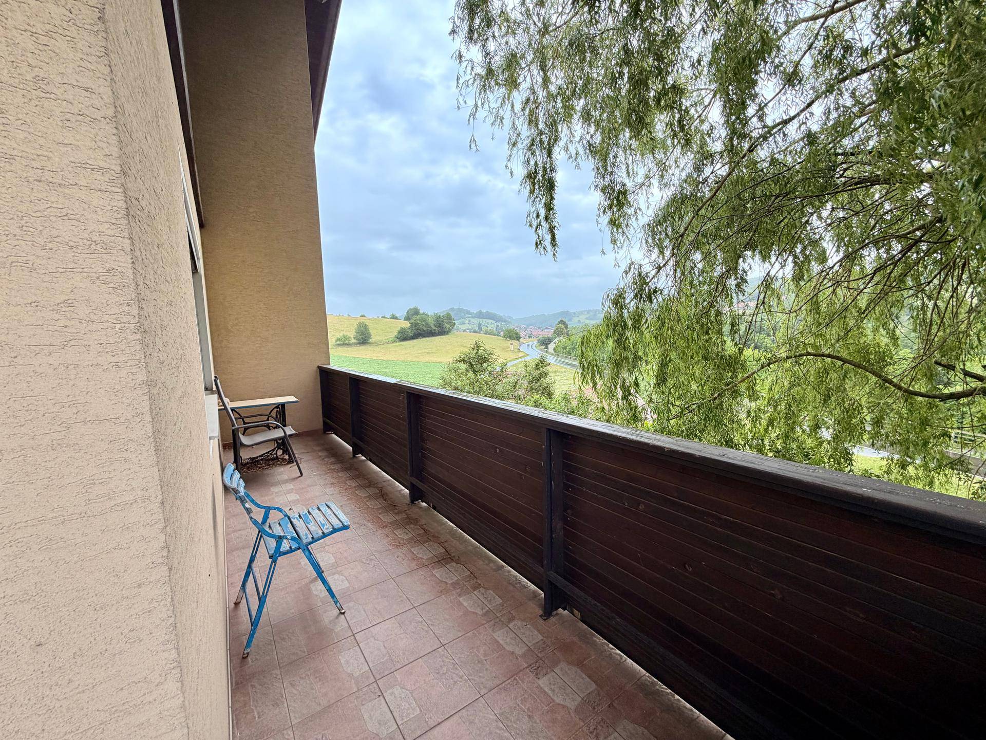 Balkon mit Fliesenboden und Sitzgelegenheiten, bietet einen weiten Blick auf die grüne Landschaft.