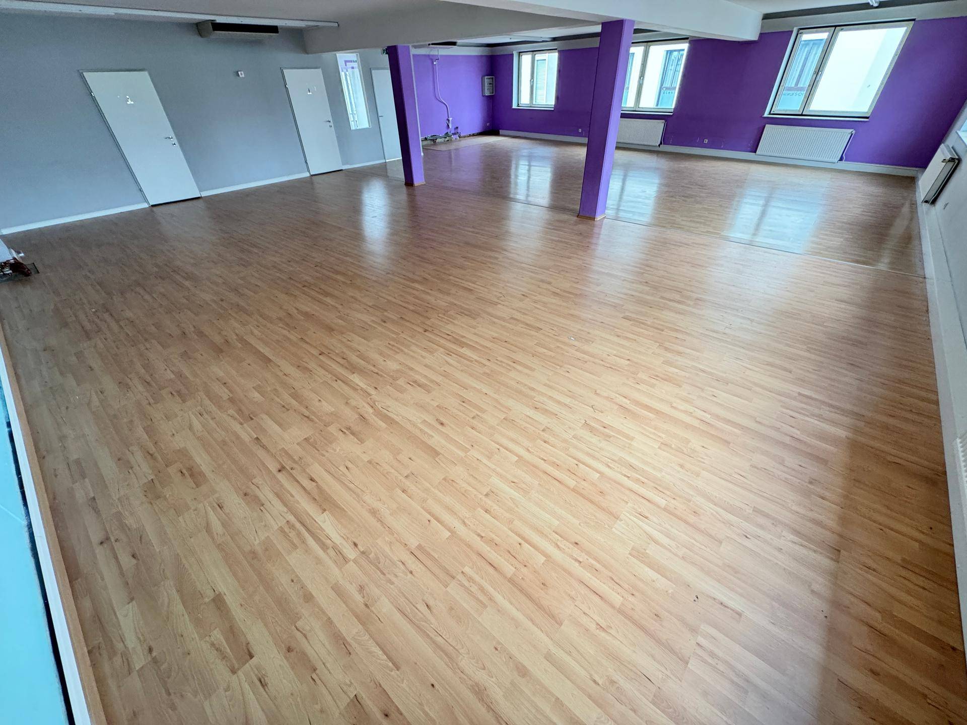Weitläufiger, leerer Raum mit hellem Laminatboden und verschiedenen Wandfarben.