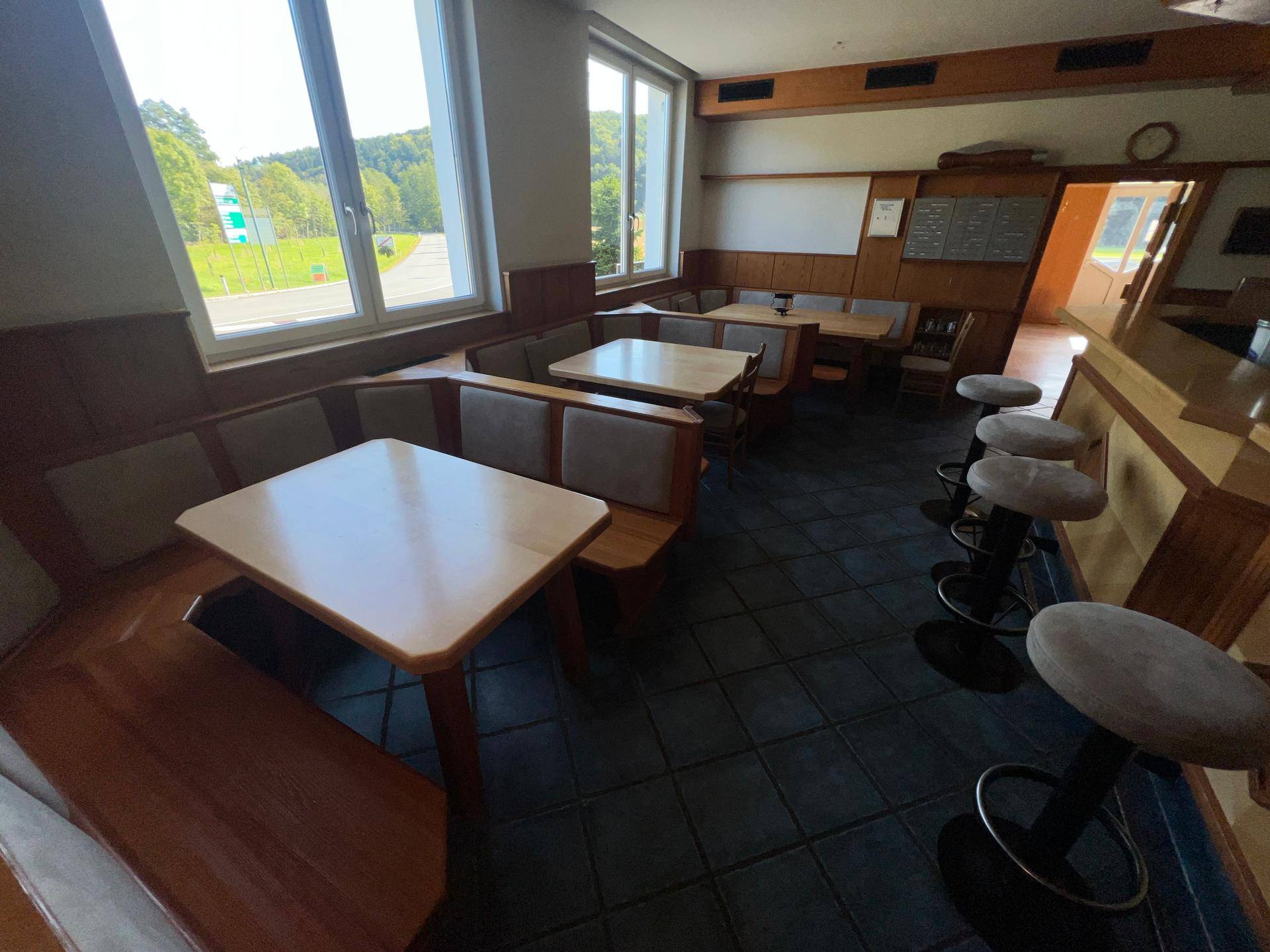 Gemütlicher Barbereich mit Holztischen, Bänken und Barhockern, ideal für gesellige Runden.