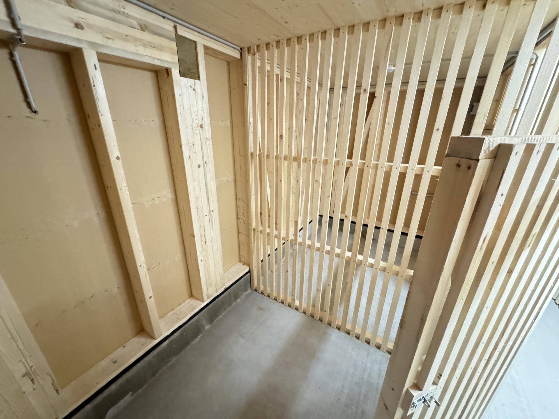 Abstellraum mit Holzlattenkonstruktion und Betonboden, ideal für Lagerzwecke.