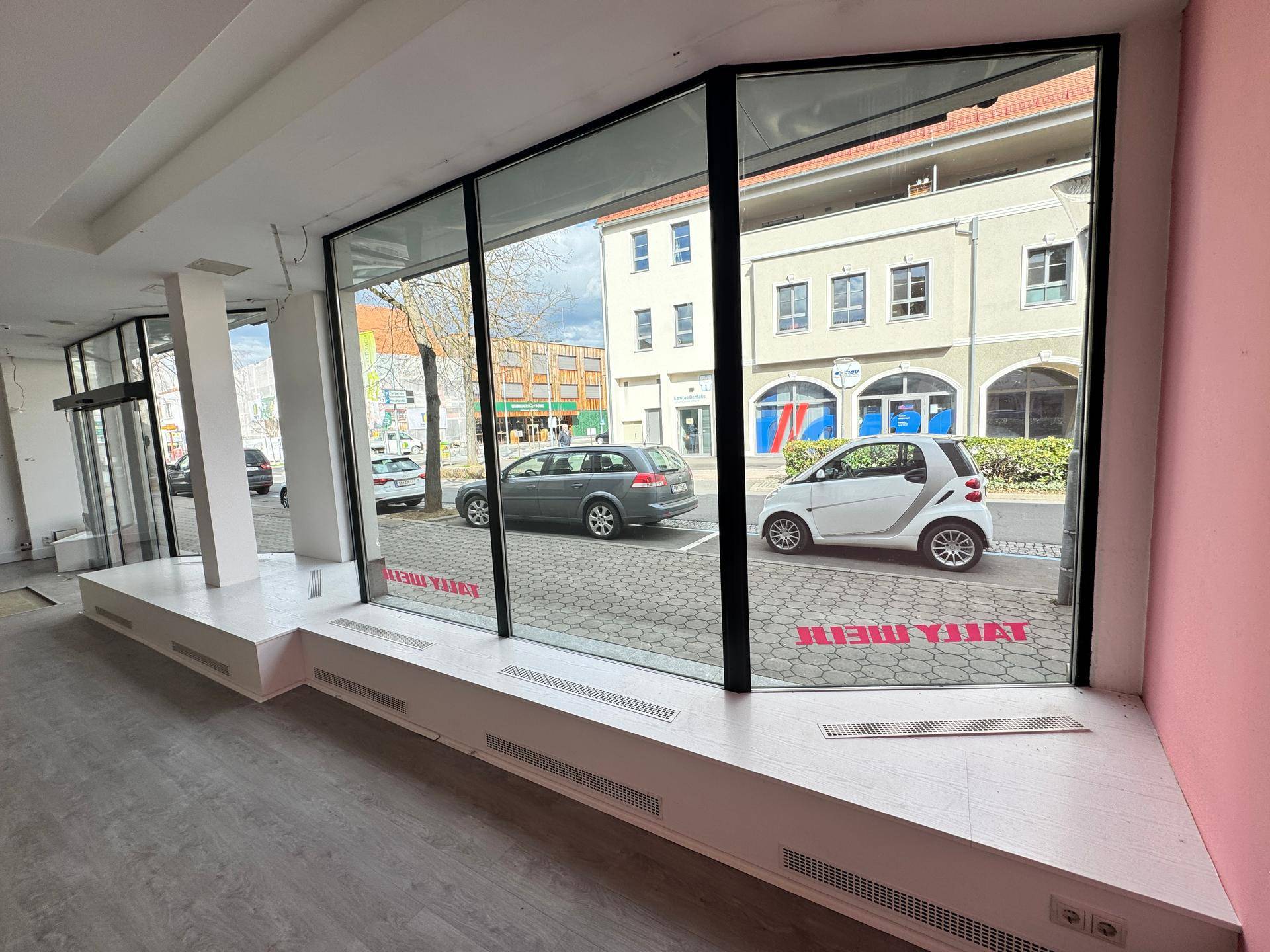 Detailansicht der großen Schaufensterfront mit Blick auf die Straße und parkende Autos.