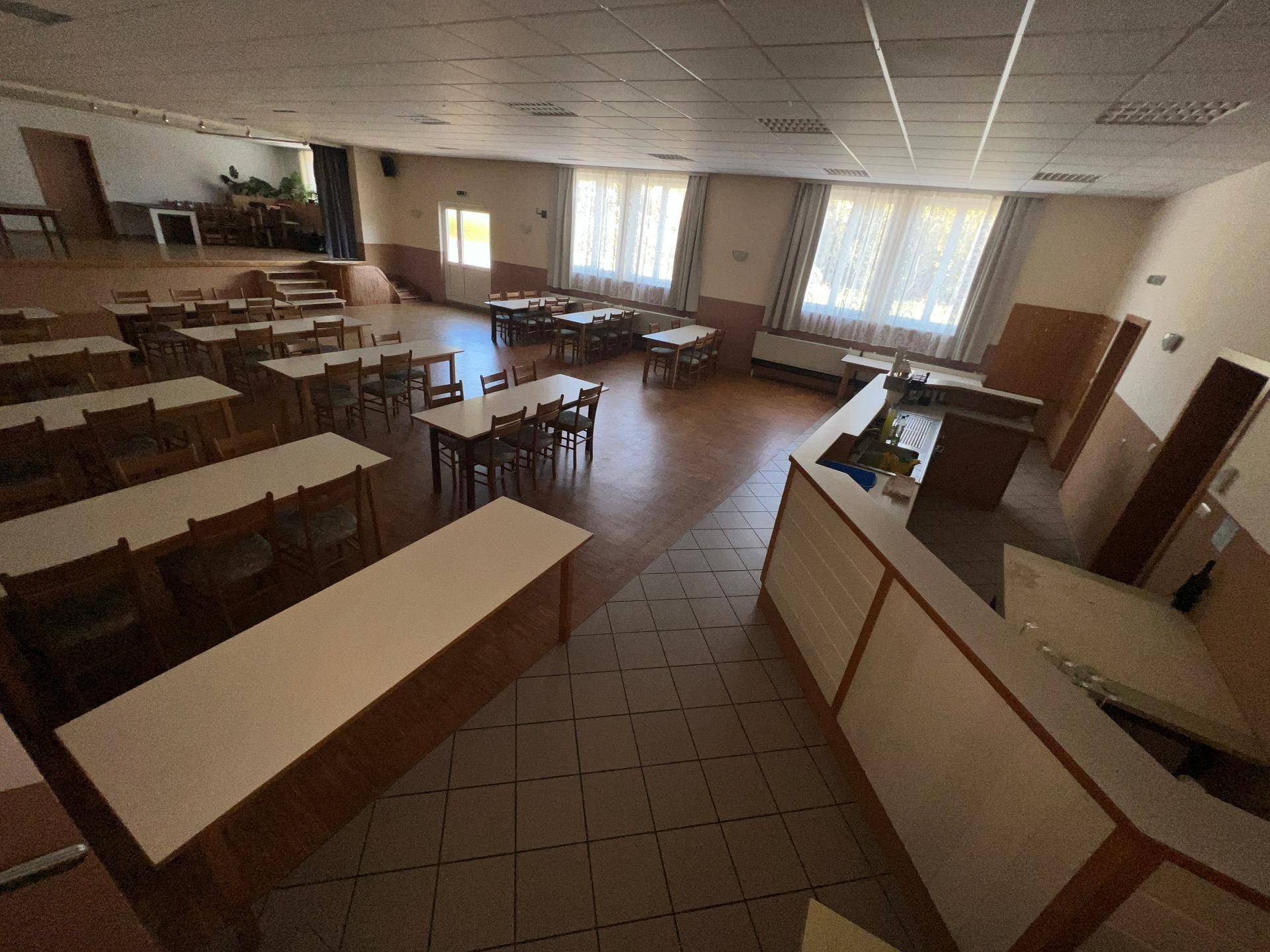 Geräumiger Speisesaal mit Tischen, Stühlen und einer Theke, bereit für Gäste.