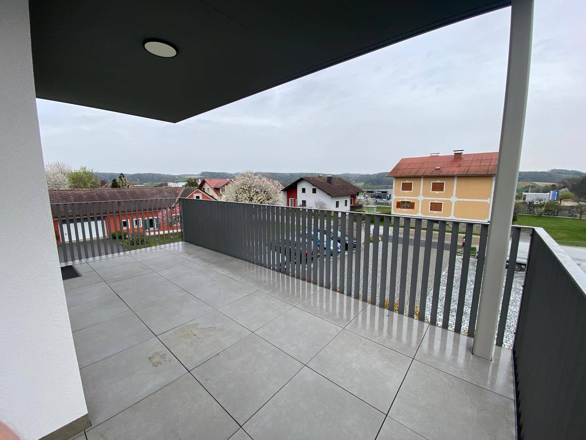 Geräumiger Balkon mit Fliesenboden und Blick auf die umliegende Wohngegend.