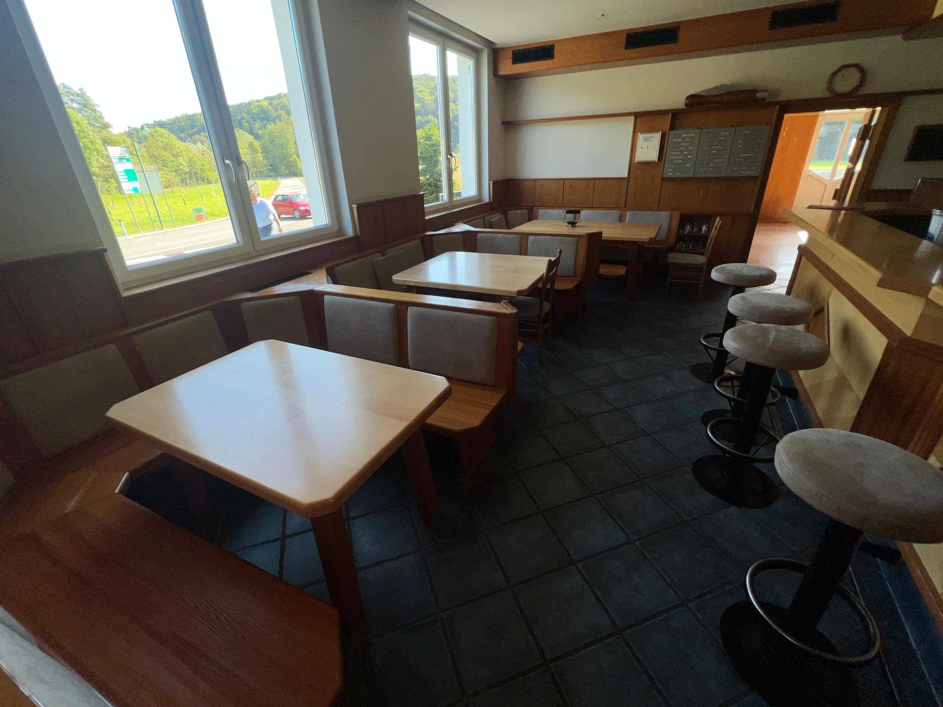 Gemütlicher Essbereich mit Sitzbänken, Tischen und großen Fenstern, angrenzend an die Bar.