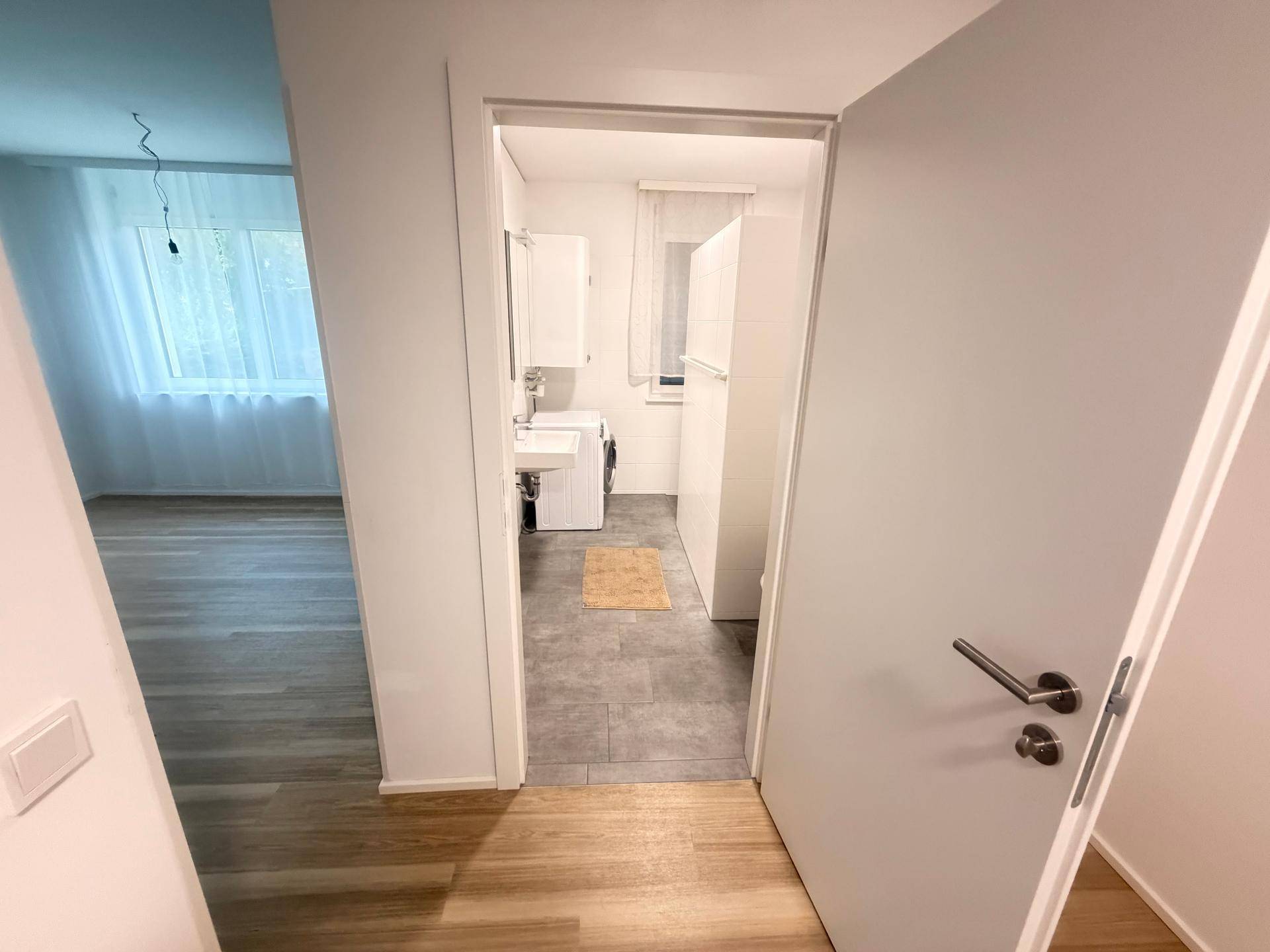 Blick in ein Badezimmer oder einen Hauswirtschaftsraum mit Waschmaschine und Fenster.