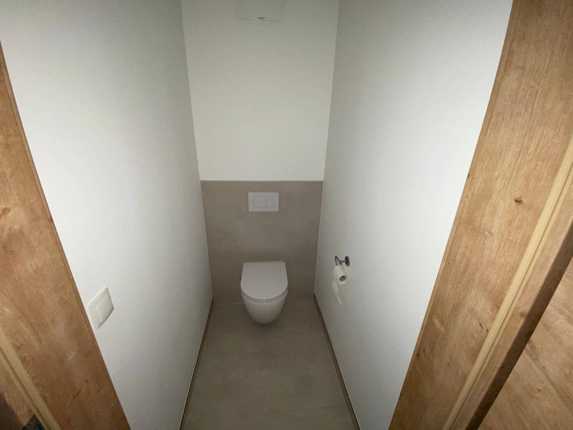 Modernes Gäste-WC mit wandhängender Toilette und Fliesenboden in neutralen Farben.