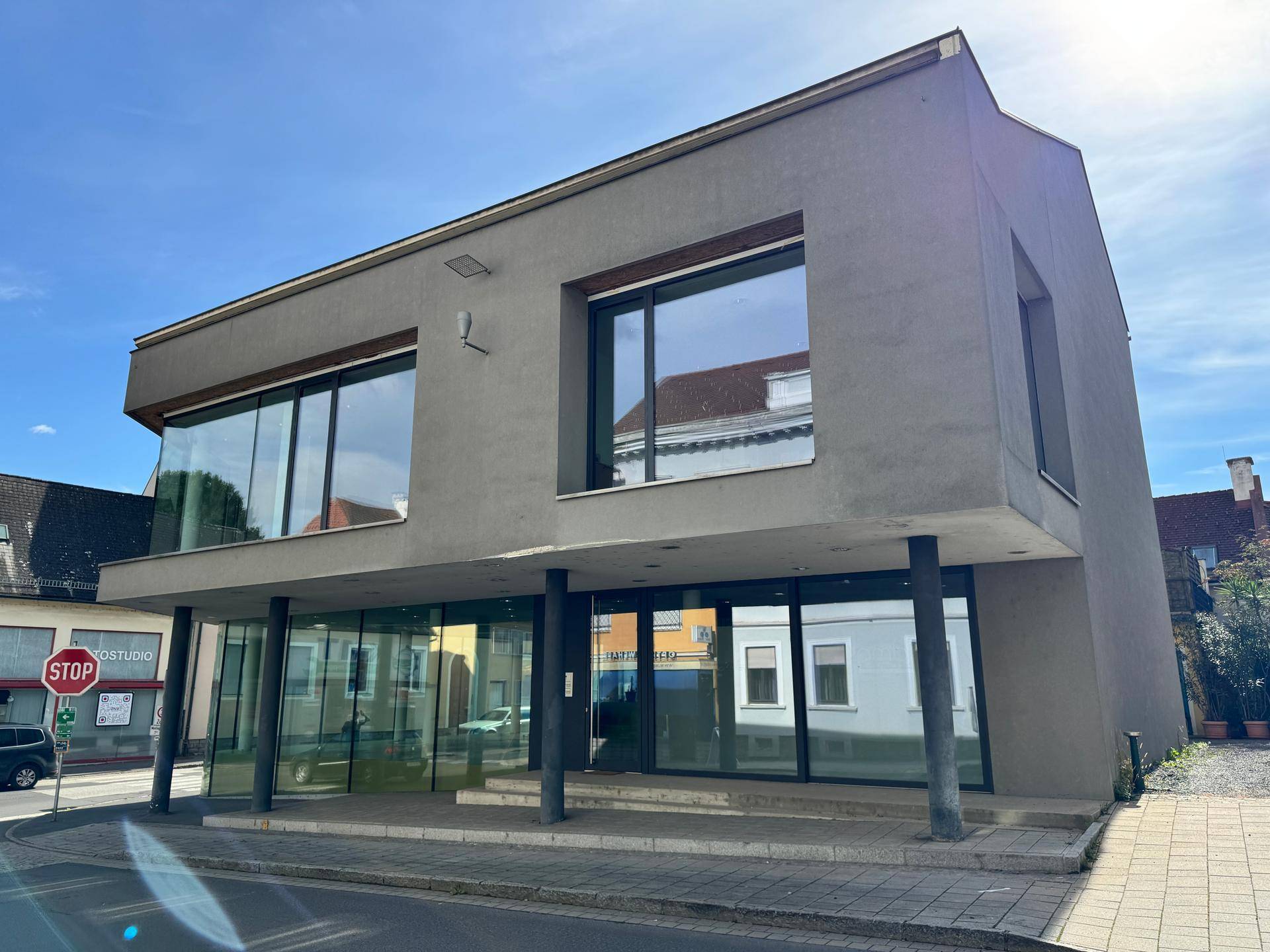 Ansicht des modernen Geschäftsgebäudes mit großen Fensterfronten und schlichter Fassade unter blauem Himmel.