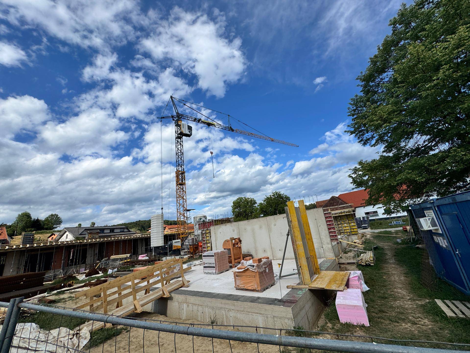 Baustelle mit Kran, Betonwänden und Baumaterialien, bereit für weitere Bauphasen.
