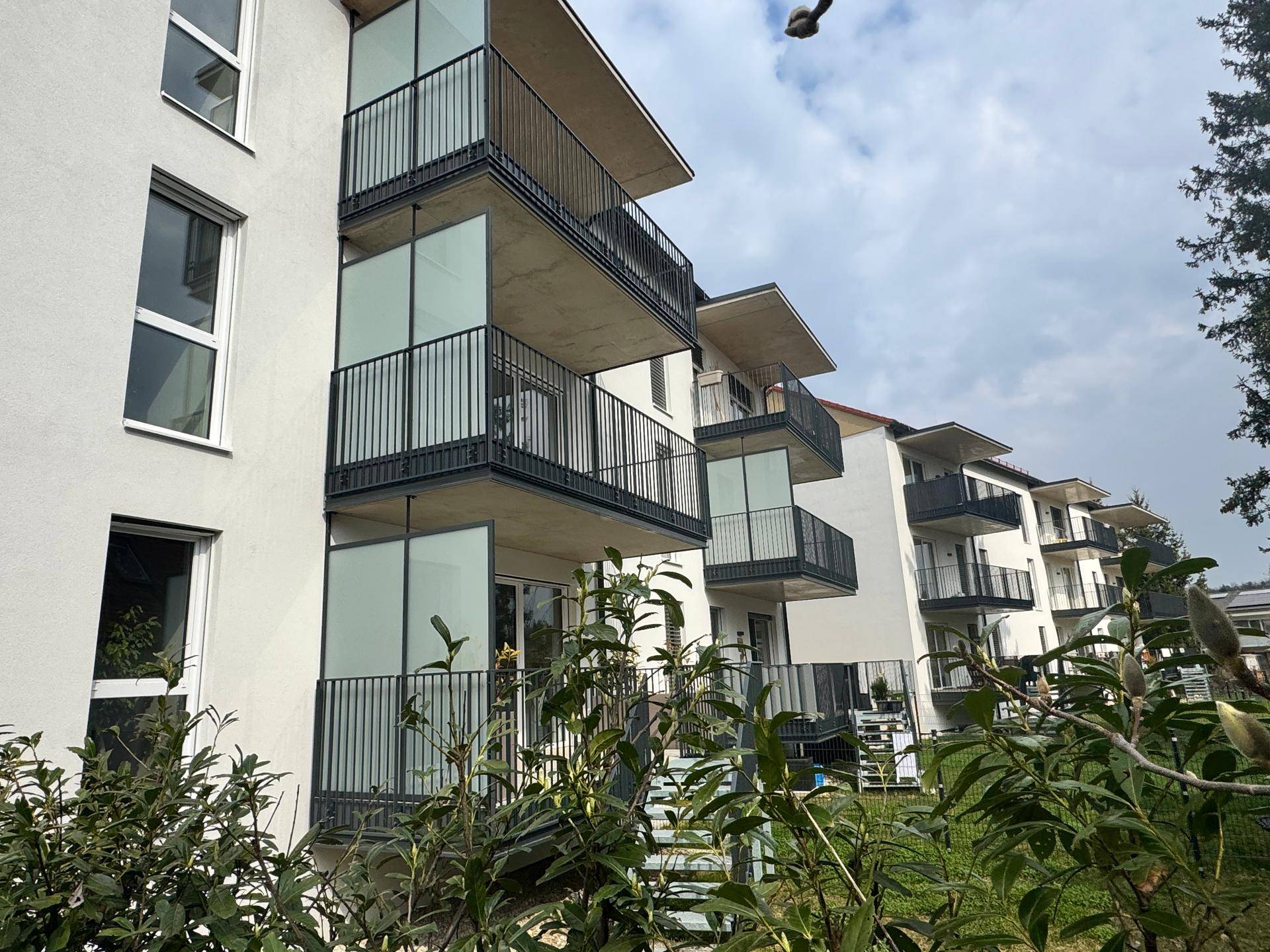 Moderne Wohnanlage mit mehreren Balkonen und grüner Umgebung.