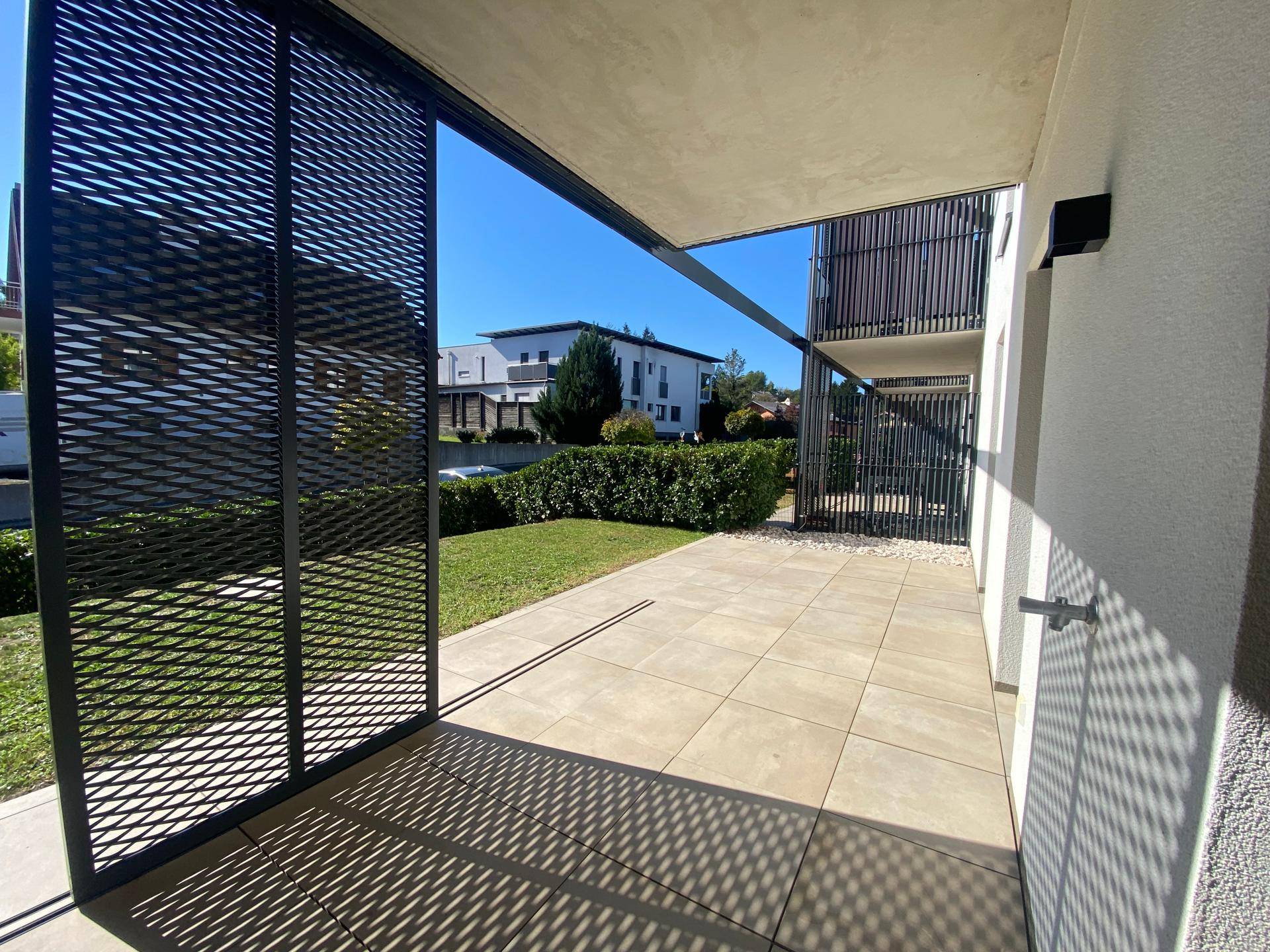 Überdachte Terrasse mit modernen Metallgittern und Blick auf die umliegende Wohngegend.