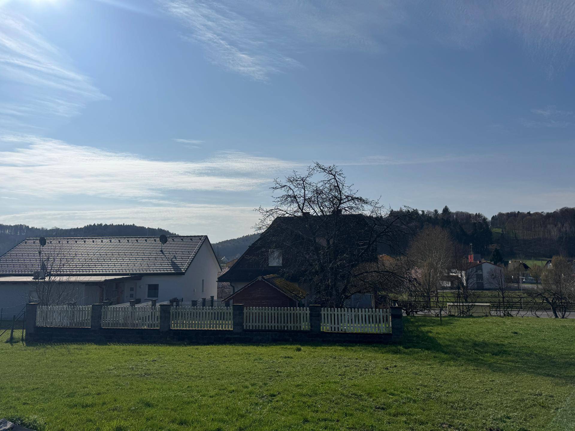 Weitläufiger Blick auf das Haus und die ländliche Umgebung mit grünen Wiesen und Bäumen.