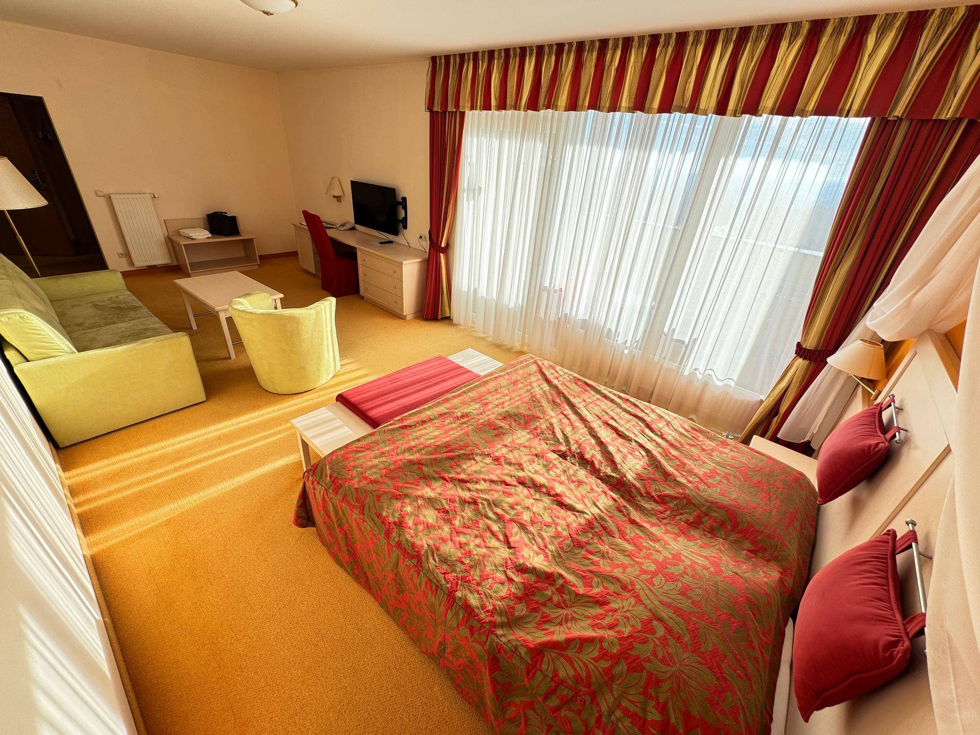 Schlafzimmer mit Doppelbett, Sitzbereich und großen Fenstern.