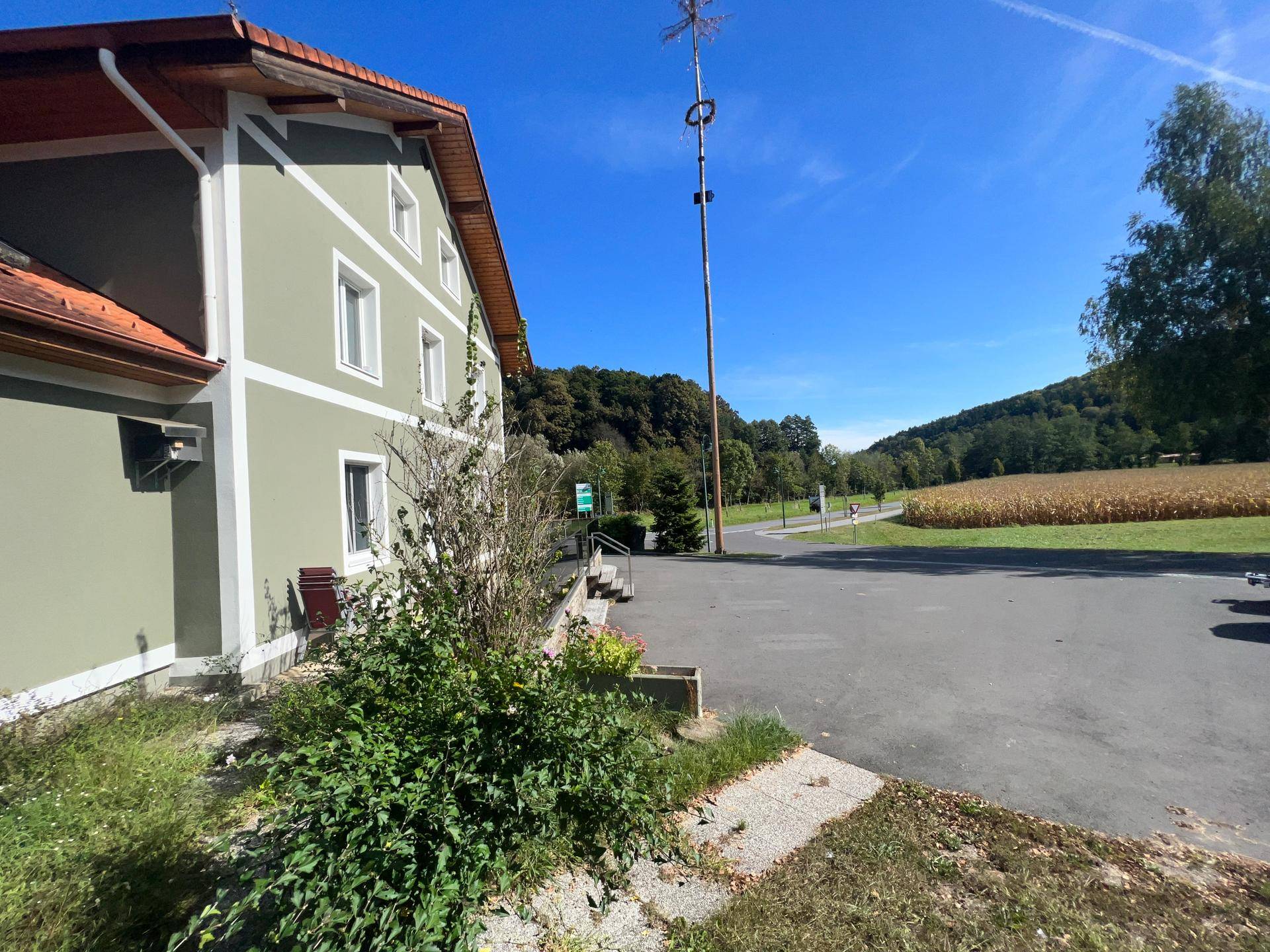 Seitenansicht des Gebäudes mit angrenzender Straße und Blick auf die ländliche Umgebung.