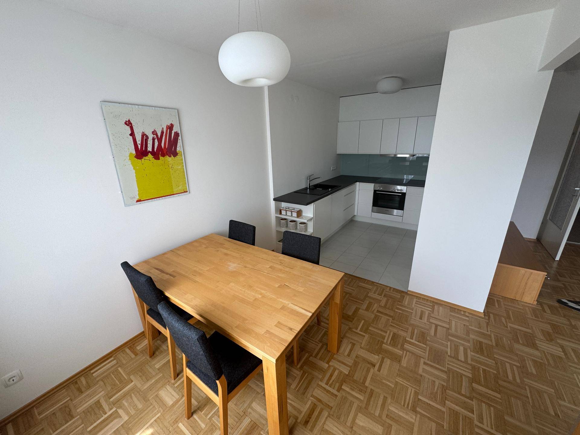 Essbereich mit Holztisch und Stühlen, offen zur Küche, mit viel Tageslicht.