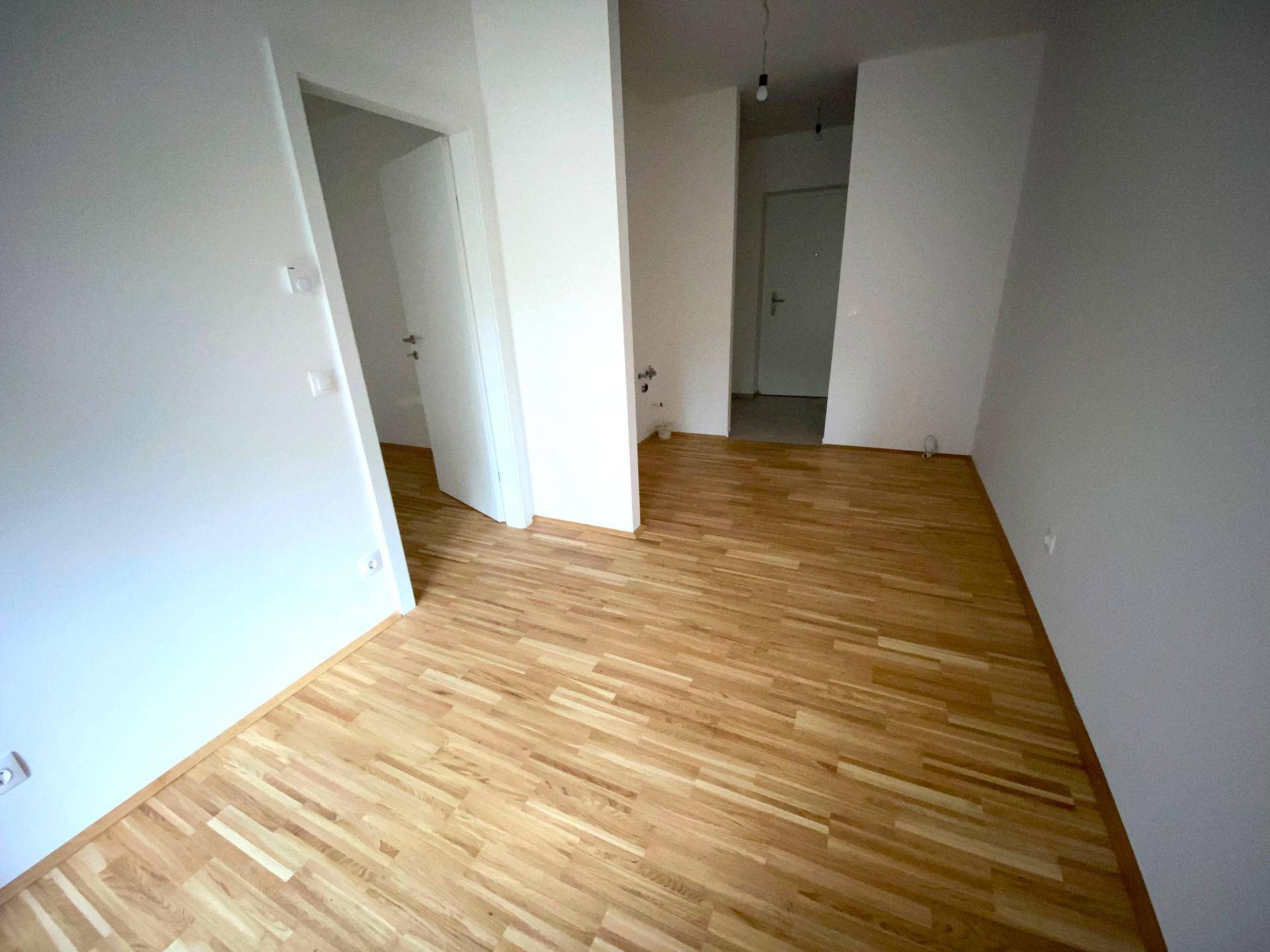 Geräumiger, heller Raum mit Parkettboden und weißen Wänden, ideal für Wohn- oder Schlafzimmer.