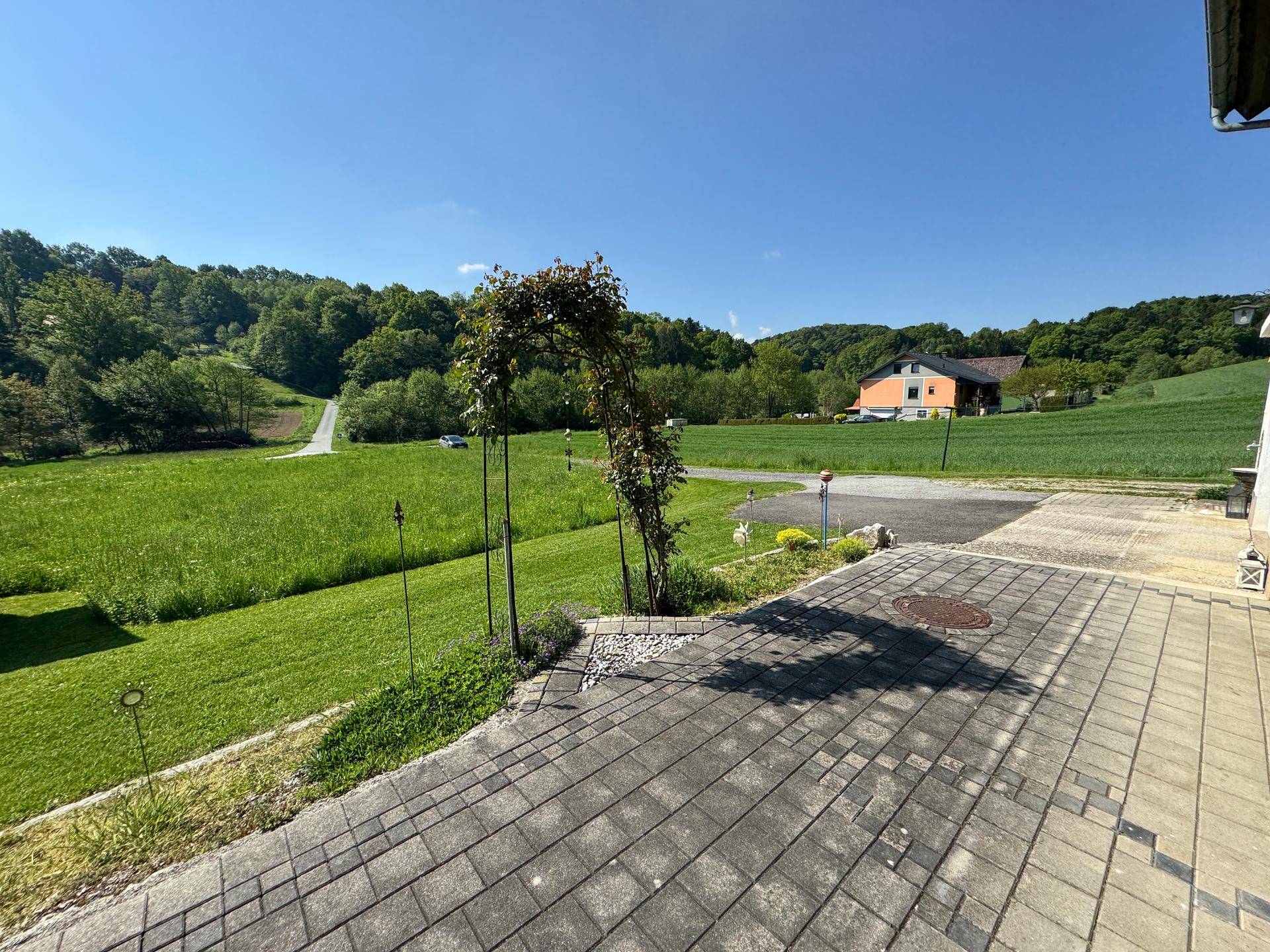 Gepflasterter Bereich vor dem Haus mit weitem Blick über die ländliche Umgebung.