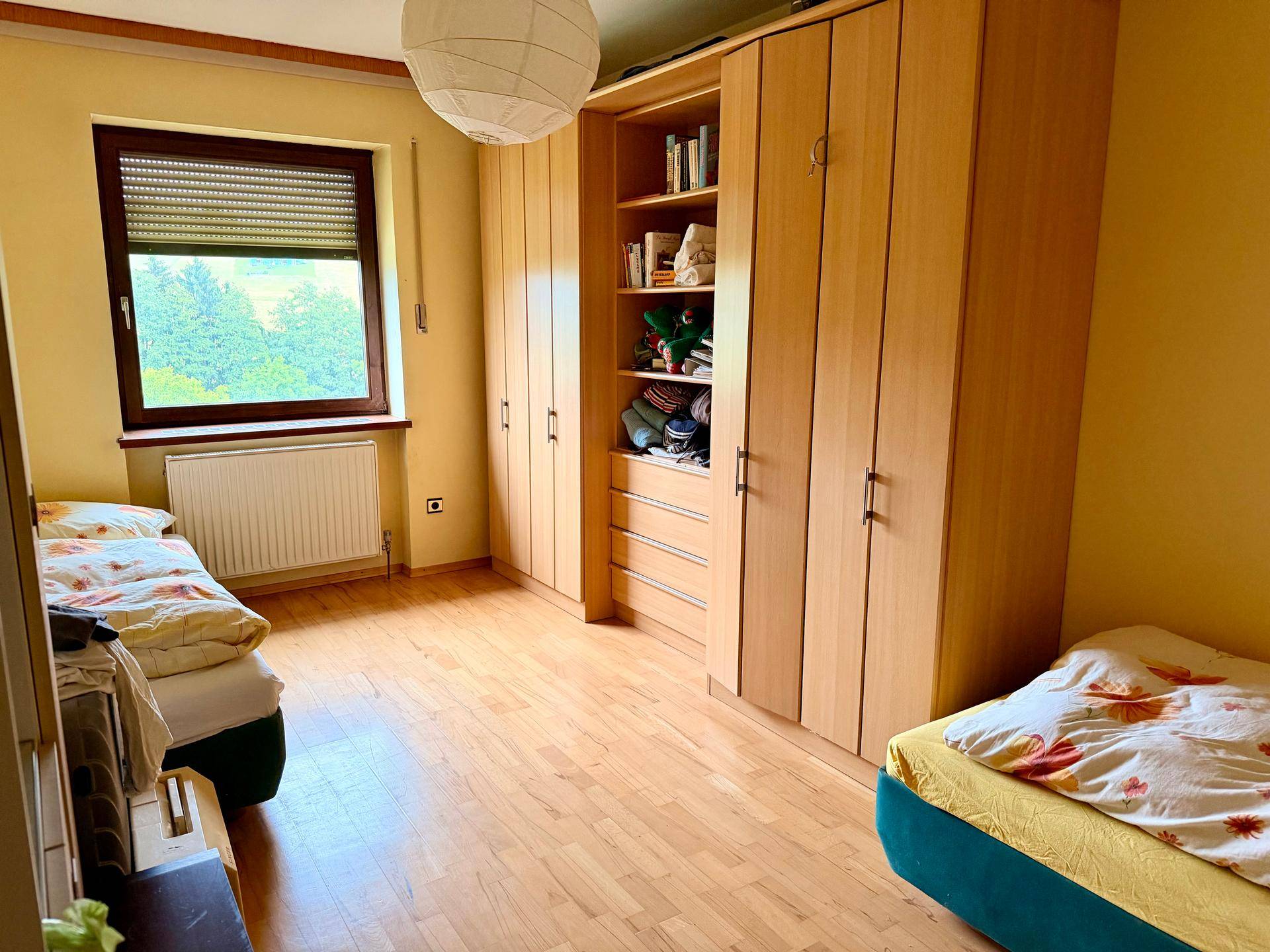 Schlafzimmer mit zwei Betten, großen Holzschränken und Laminatboden.