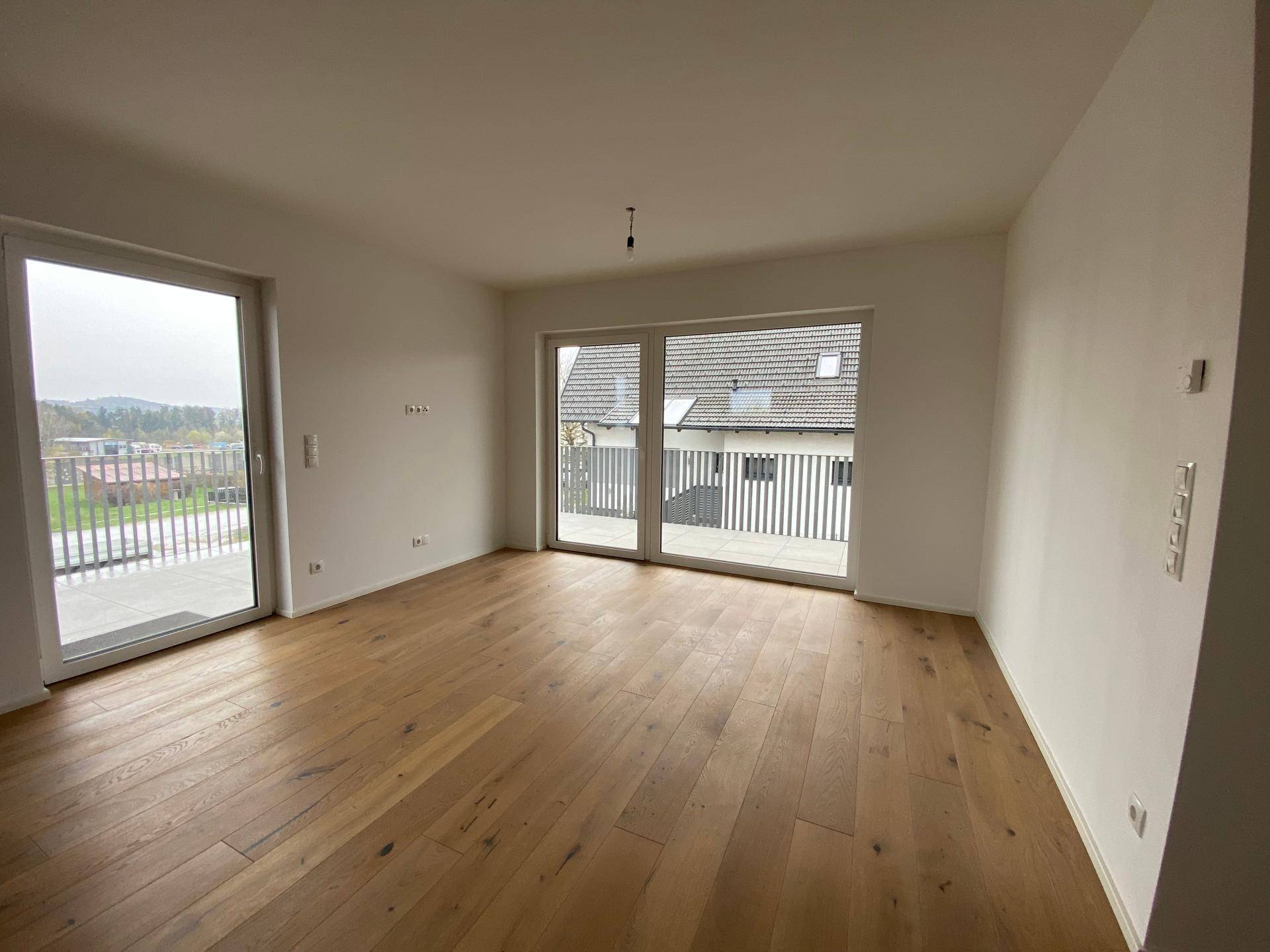 Geräumiger Wohnbereich mit großen Fenstern und Balkonzugang, der eine weite Aussicht bietet.