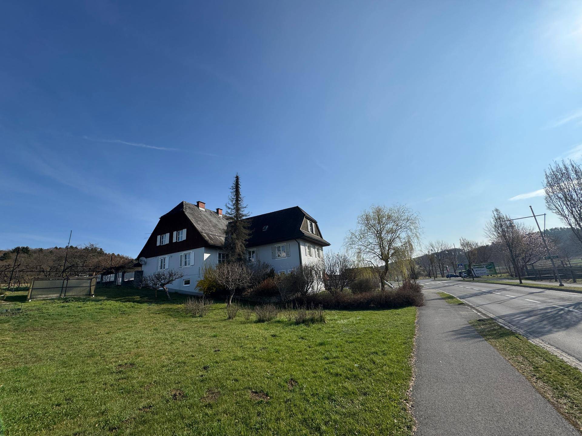 Haus mit großem Grundstück und angrenzendem Gehweg, umgeben von ländlicher Idylle.