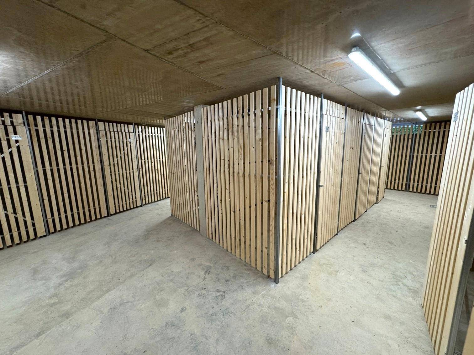 Geräumiger Abstellraum im Keller mit einzelnen Holzverschlägen und Betonboden.