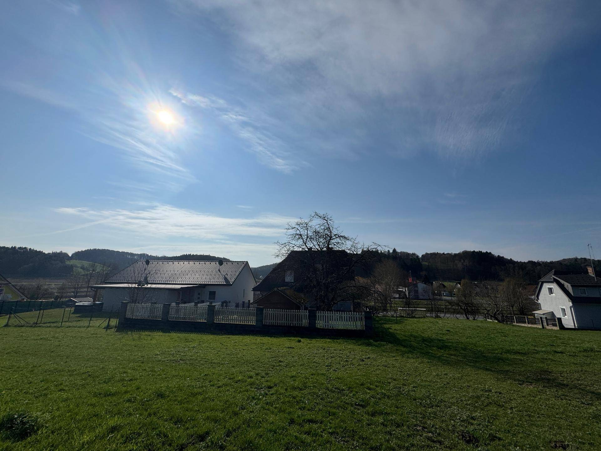Weitläufiger Blick auf das Haus und die ländliche Umgebung mit grünen Wiesen und Bäumen.