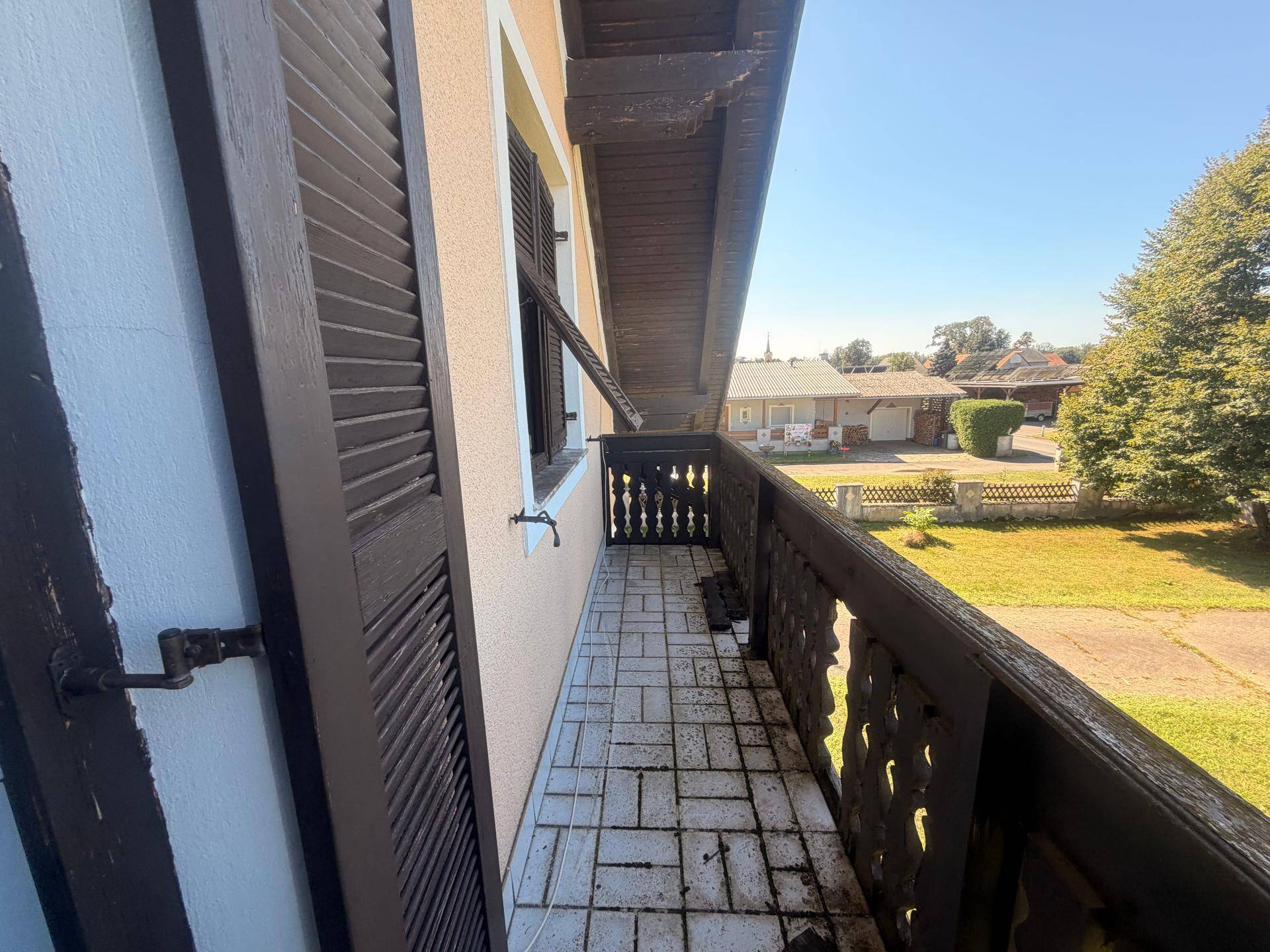 Kleiner Balkon mit traditionellem Holzgeländer und Fliesenboden.