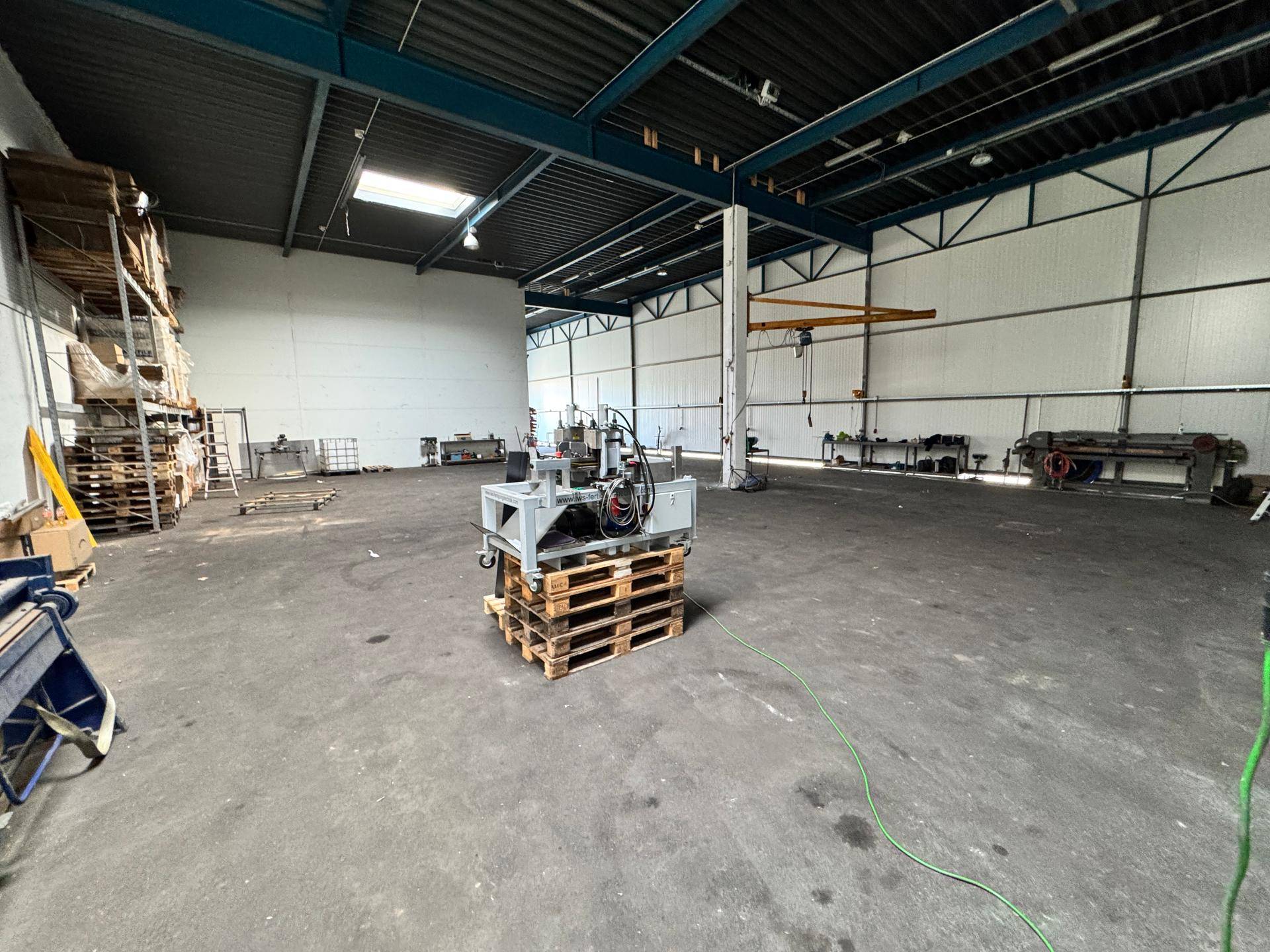 Geräumige Werkstatt mit industriellem Betonboden und Tageslicht durch Oberlichter.