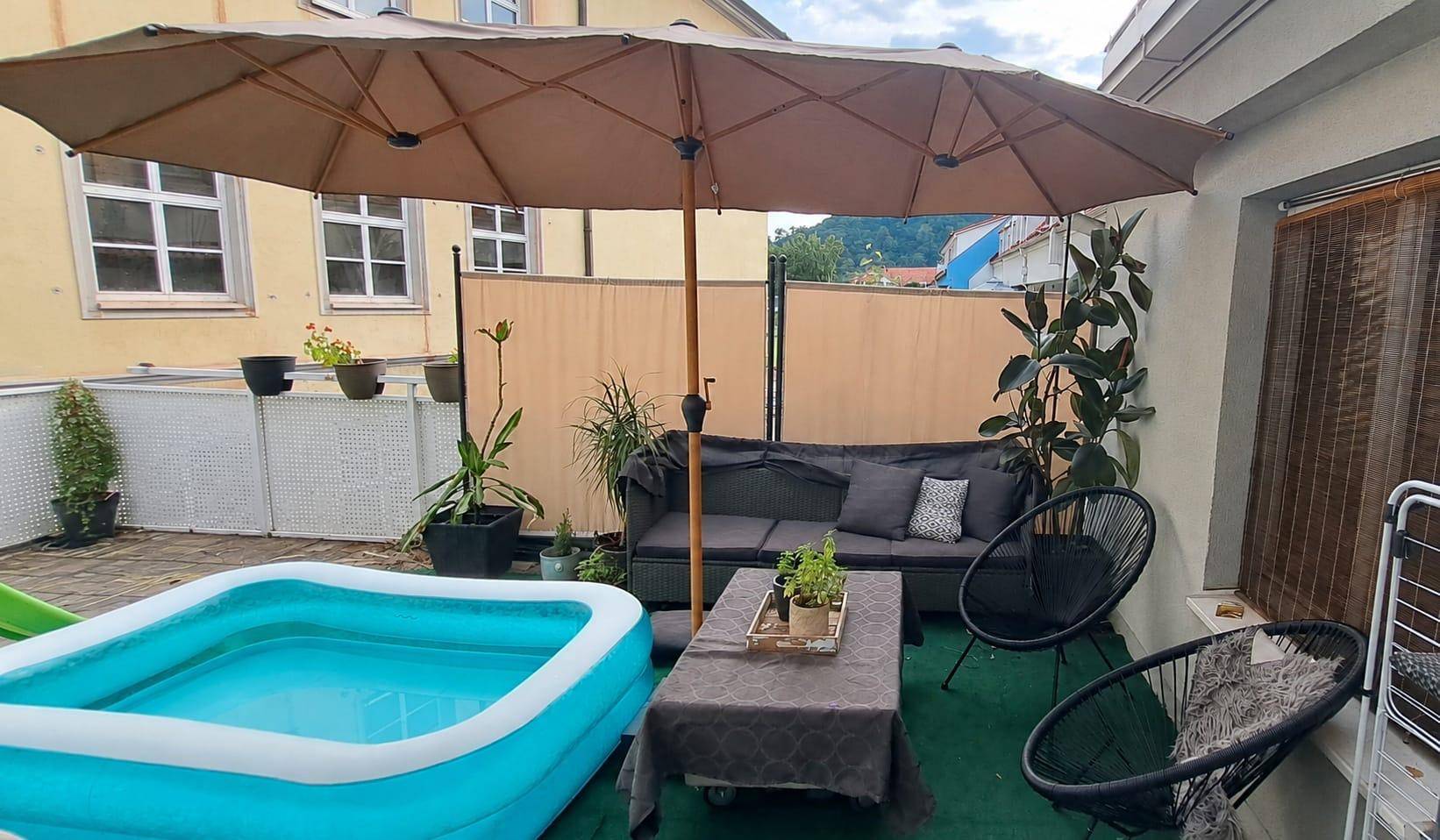 Gemütliche Terrasse mit Sonnenschirm, Outdoor-Möbeln und einem kleinen Planschbecken für entspannte Stunden.