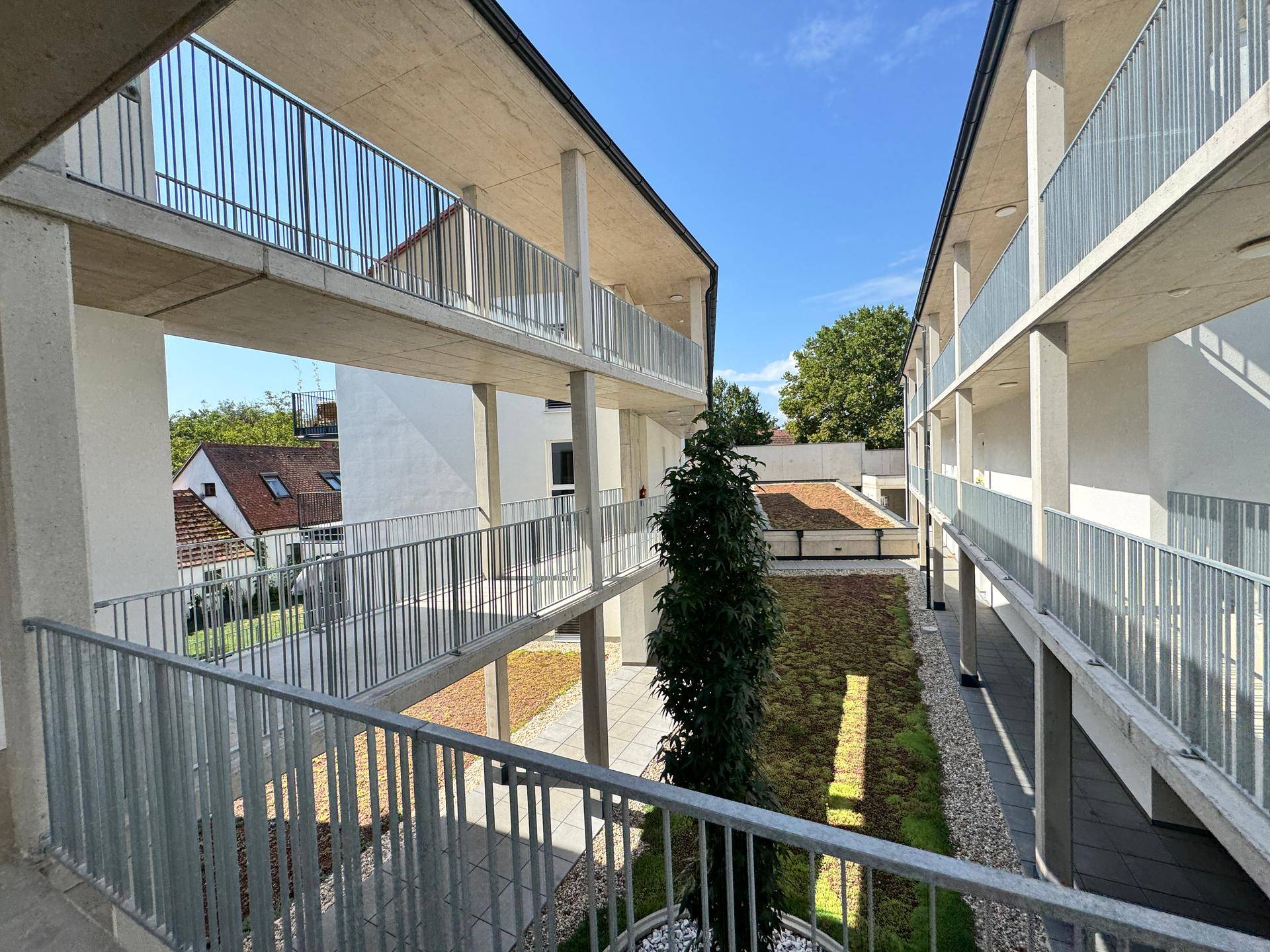 Innenhof eines modernen Wohnkomplexes mit mehreren Etagen und begrünten Flächen.