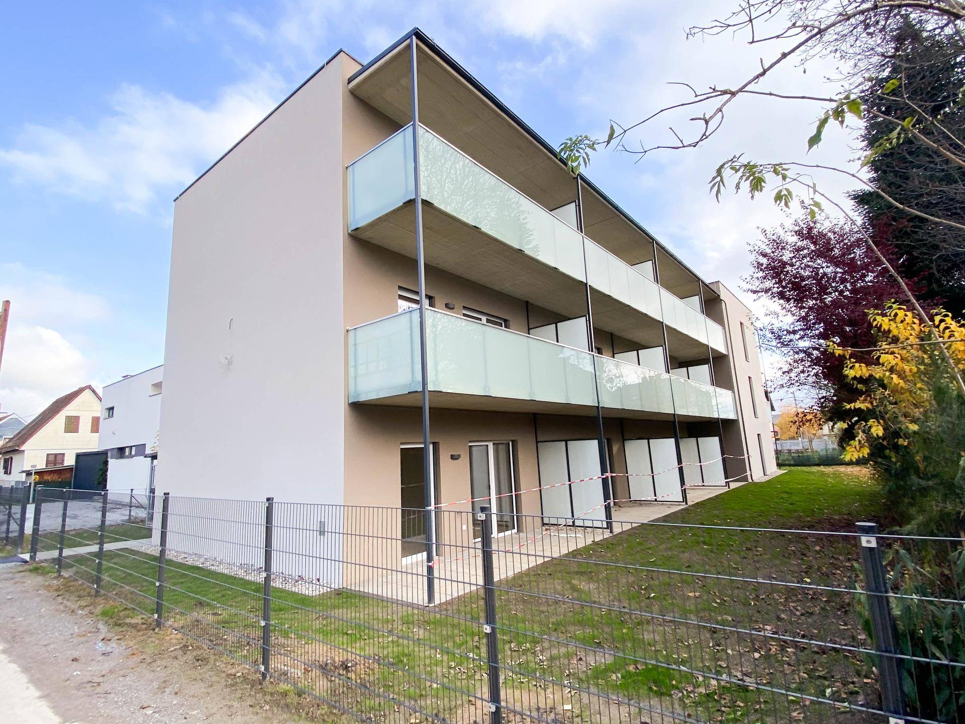 Rückansicht des modernen Mehrfamilienhauses mit Terrassen und Grünflächen.