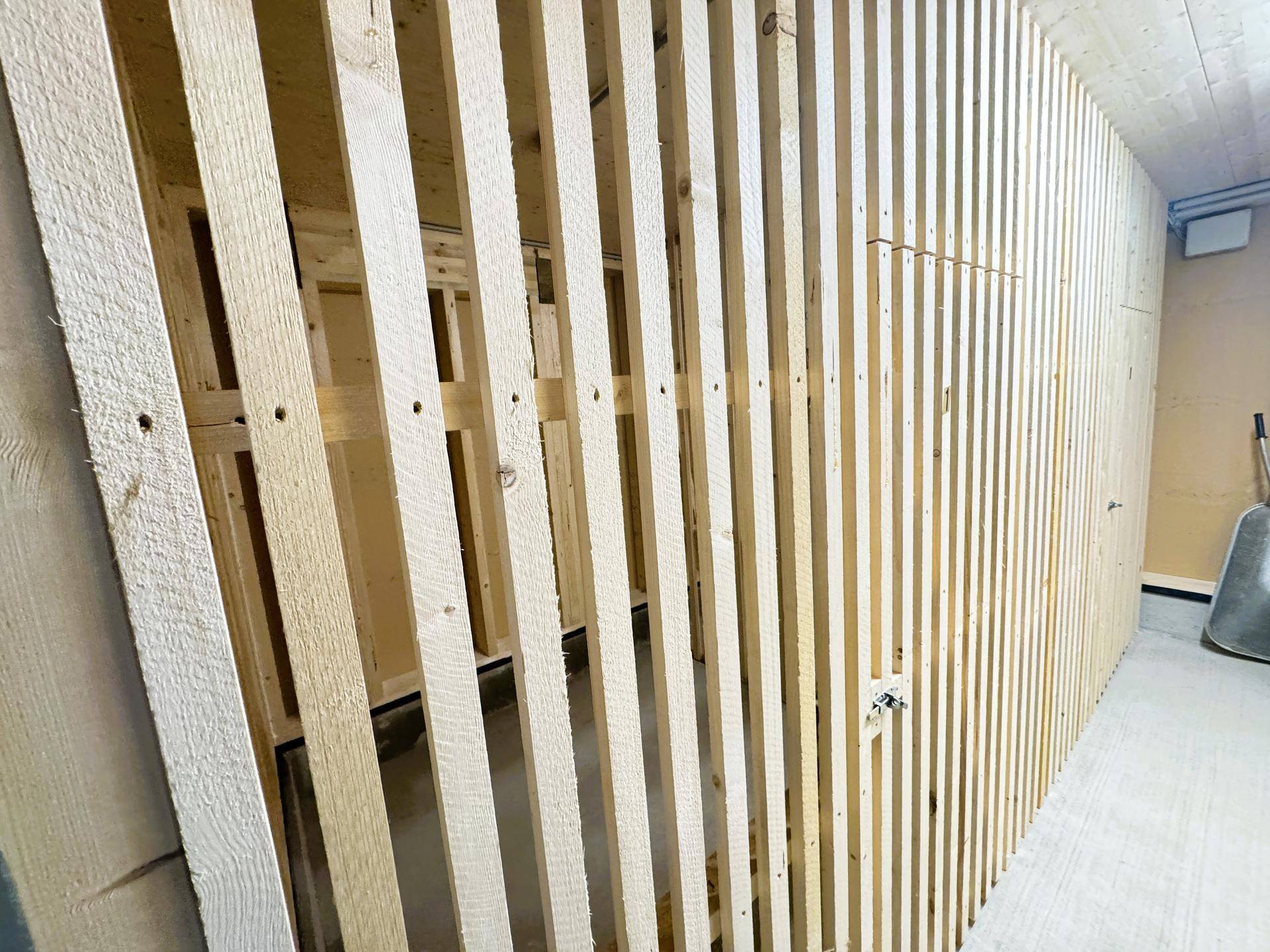 Abstellraum mit Holzlattenkonstruktion und Betonboden, bietet viel Stauraum.