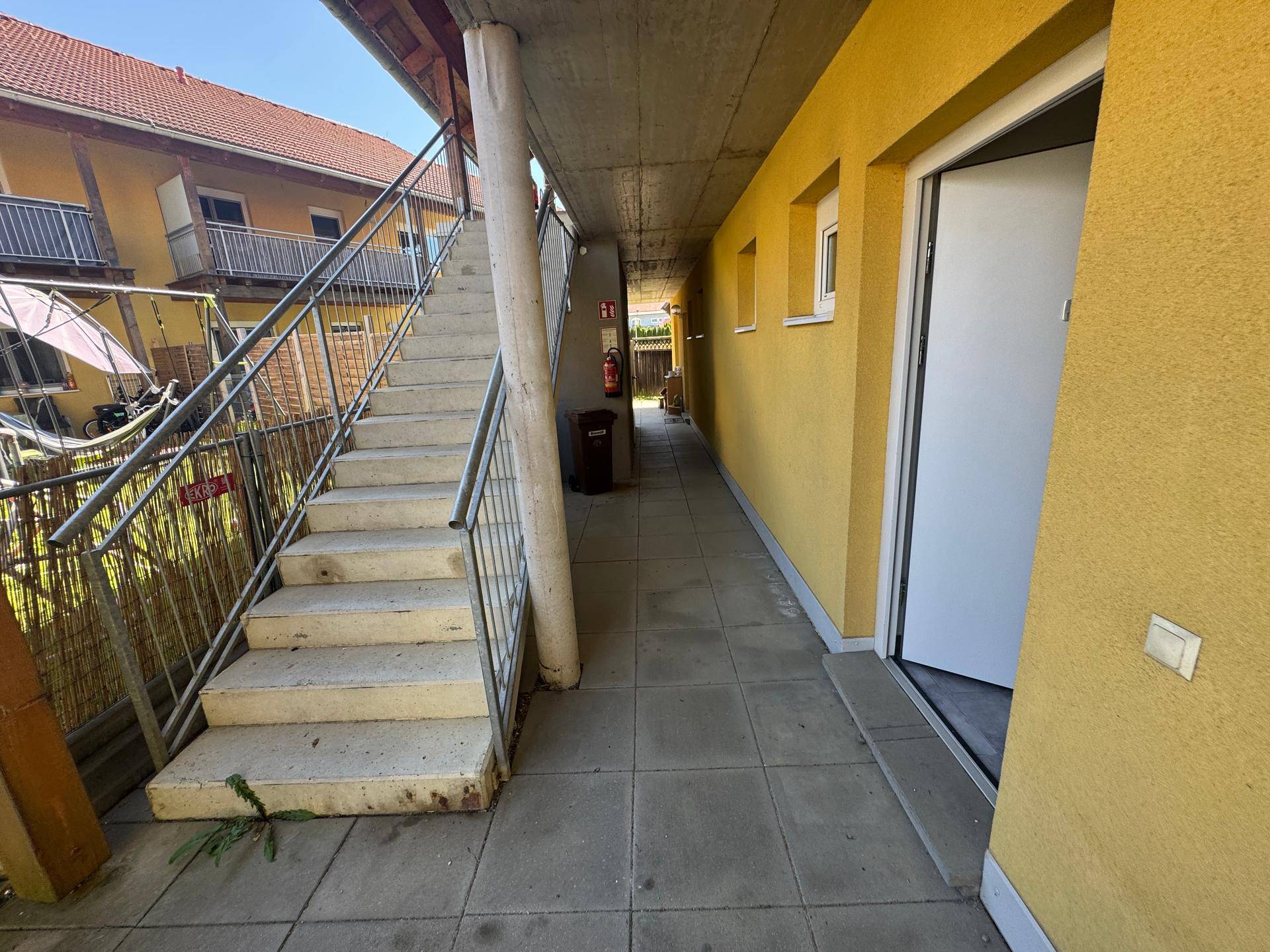 Überdachter Außenbereich mit Treppe, die zu den oberen Etagen des Gebäudes führt.