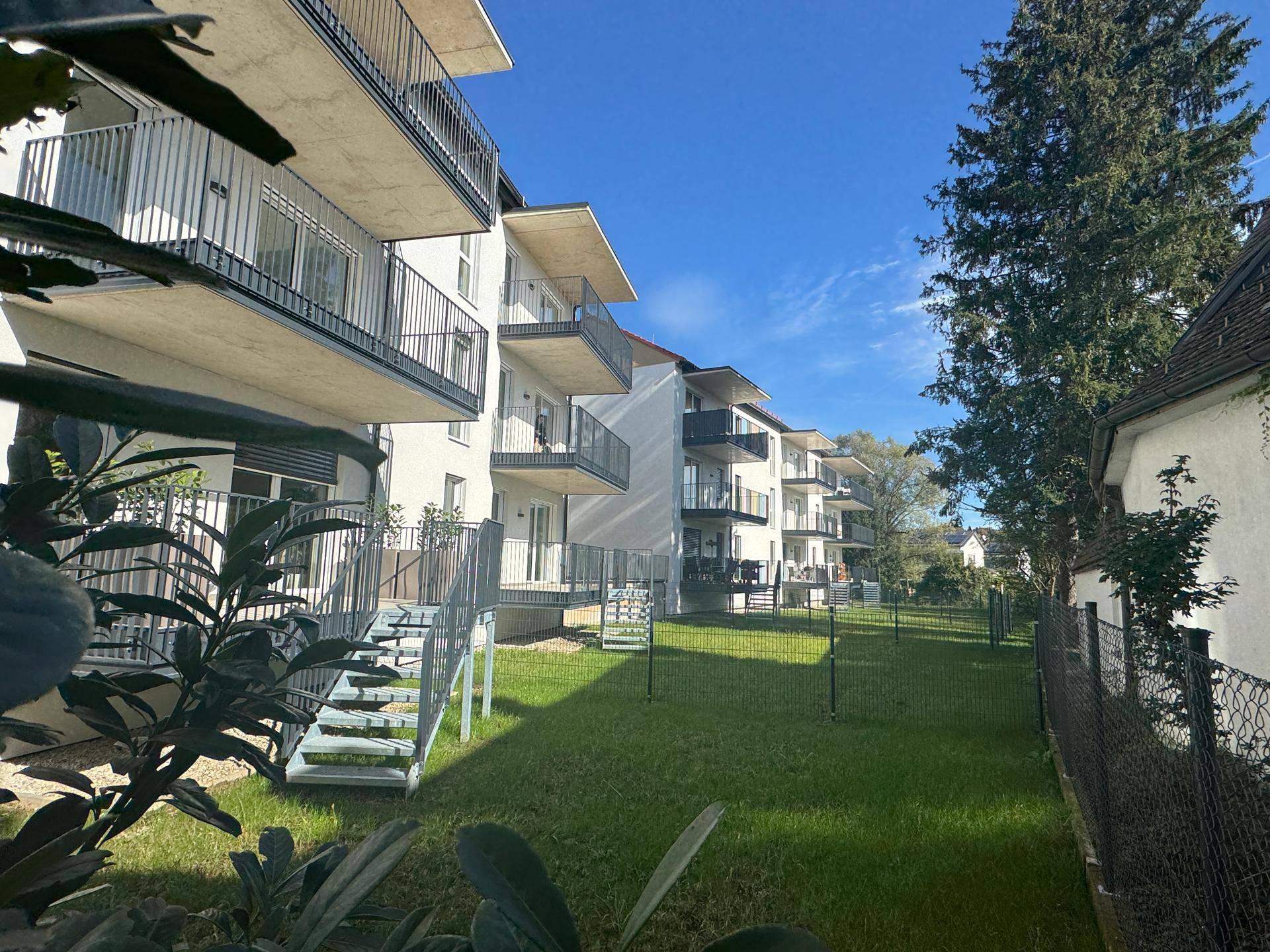 Gepflegte Rasenfläche vor den modernen Wohngebäuden mit Balkonen.